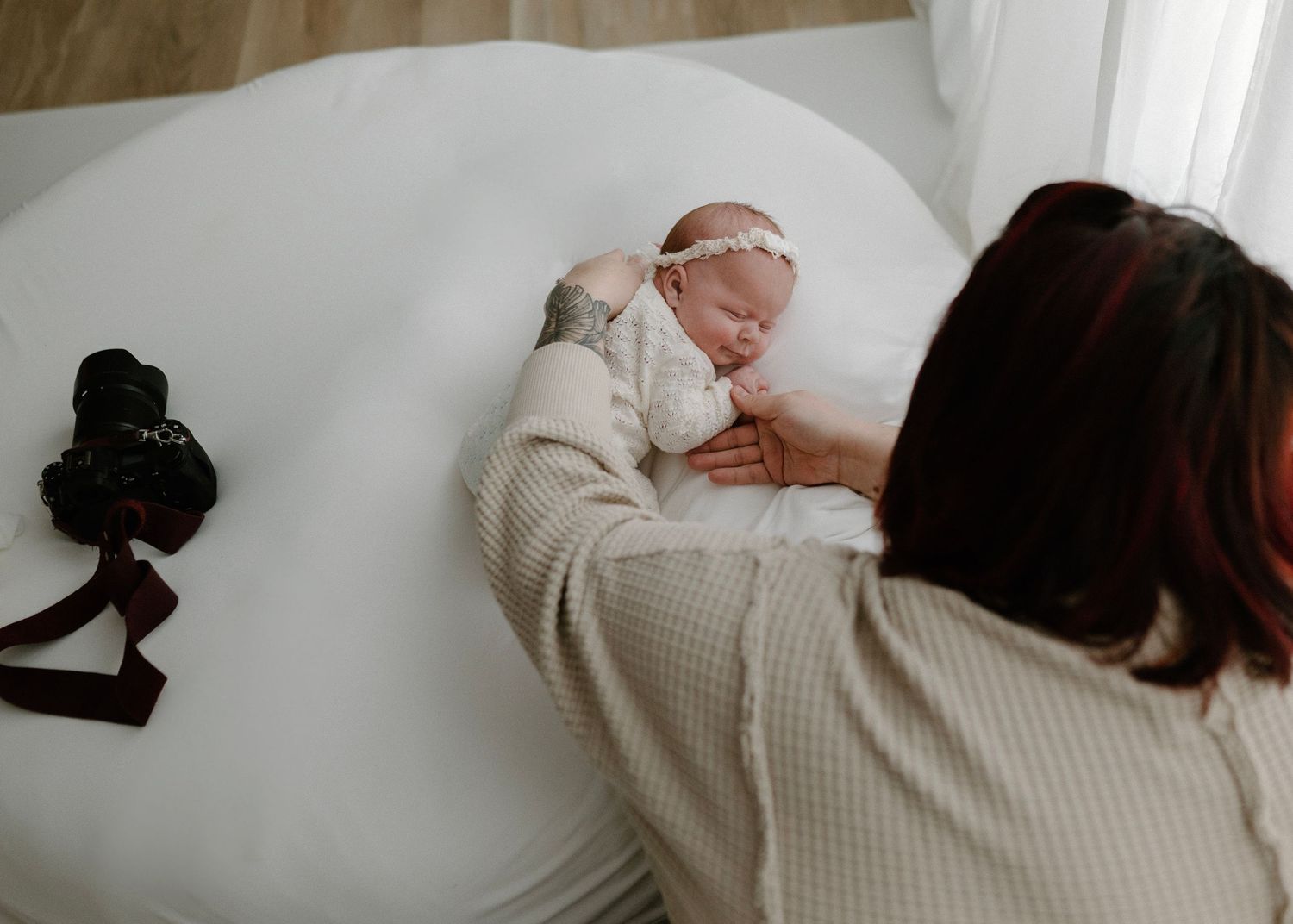 Photographer posing a newborn baby on a white surface during a professional photo session.