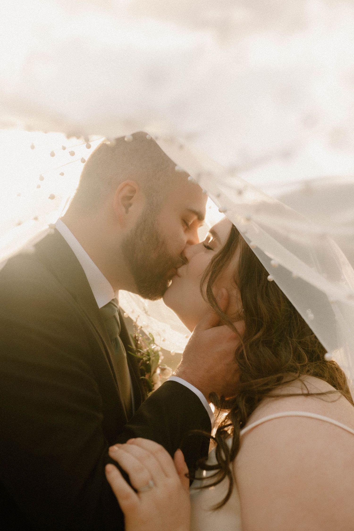 Wedding couple kiss under the veil in Alberta field