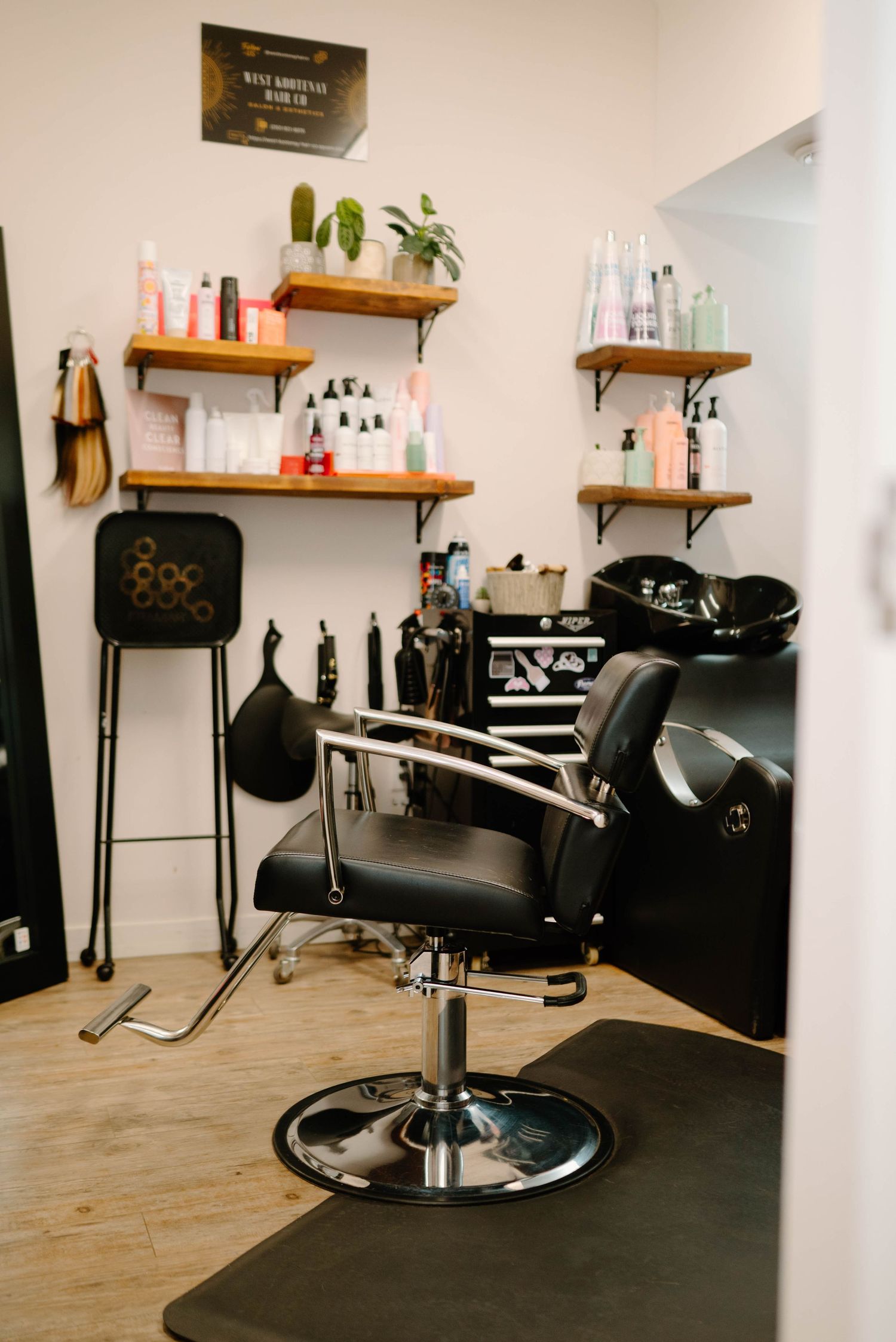 Modern hair salon interior with black styling chair, shelves of hair products, and wash basin.