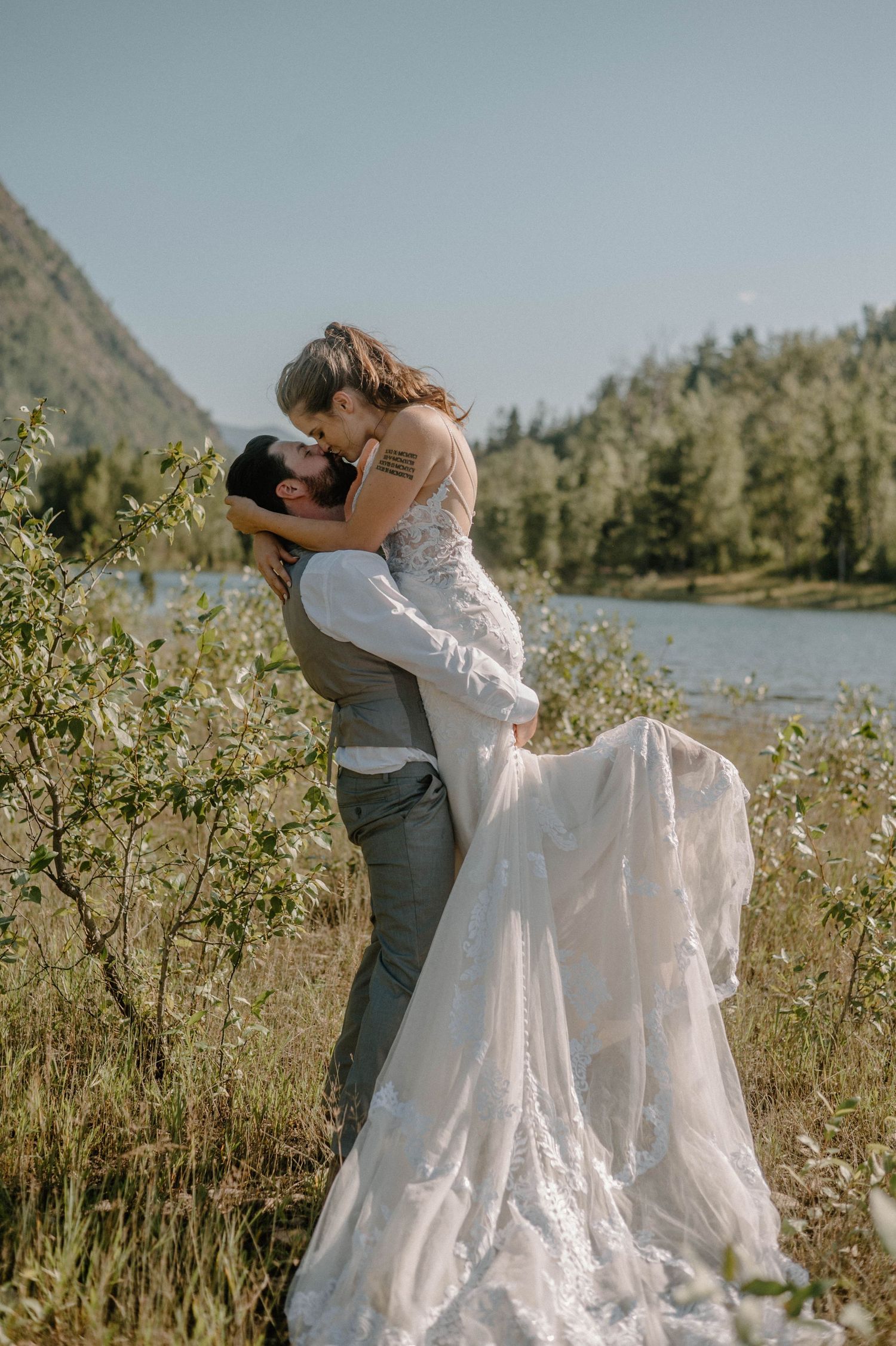 bride and groom kissing in a field in the mountains