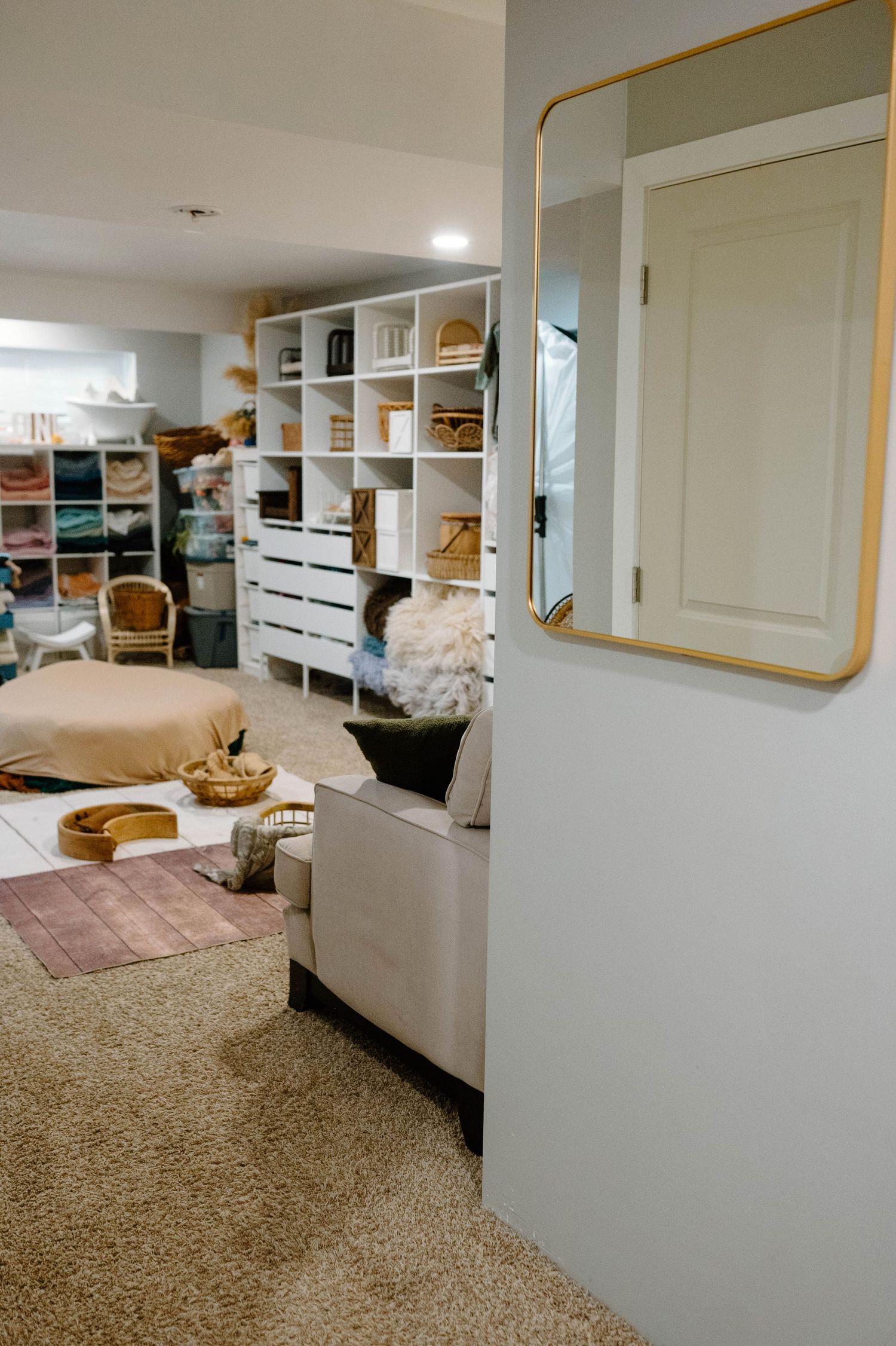 Leduc Photography studio interior featuring white shelving, gold-framed mirror, neutral sofa, and carpeted floors.