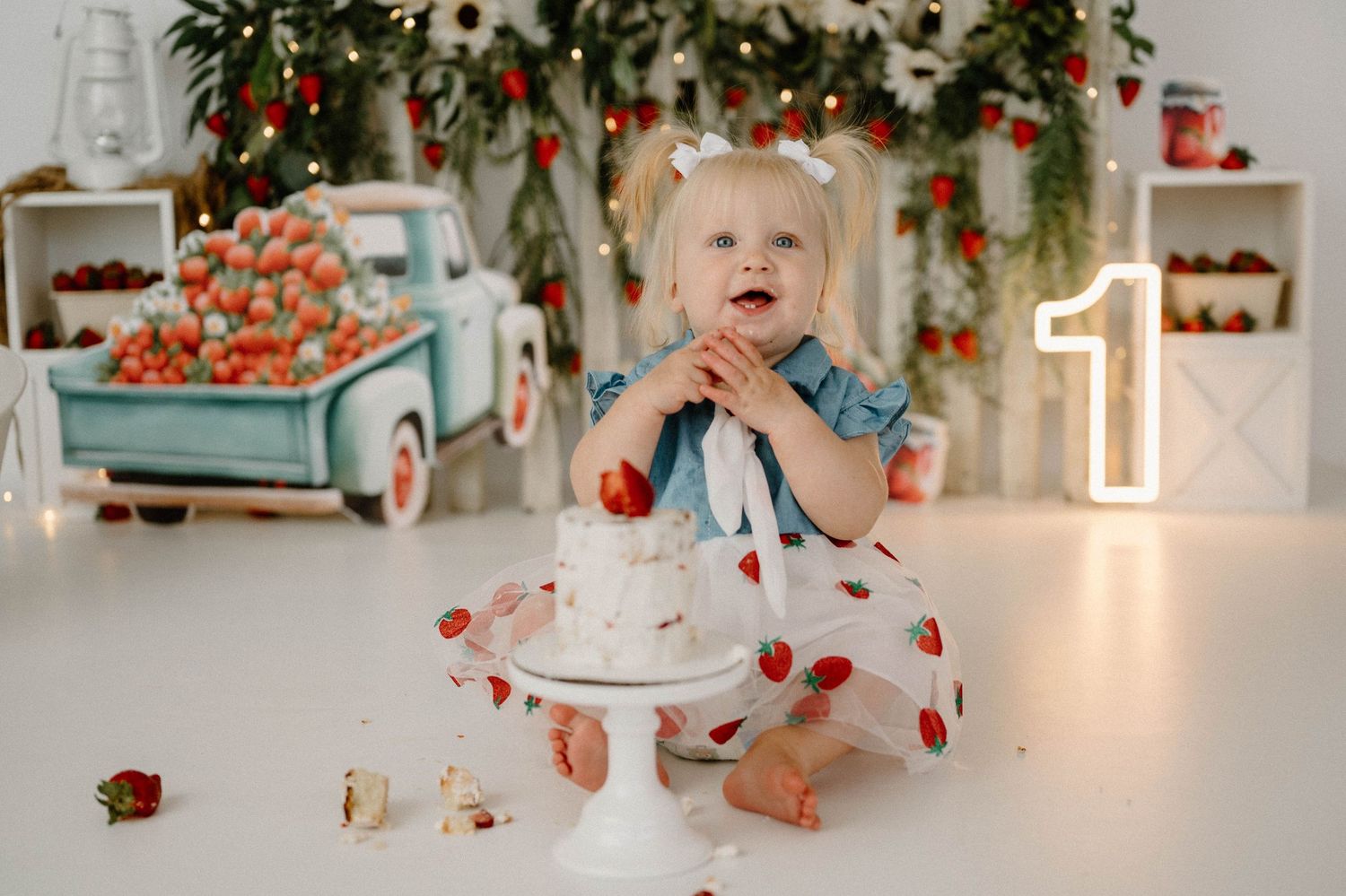 Baby girl in strawberry dress smashing cake at strawberry farm themed first birthday session.