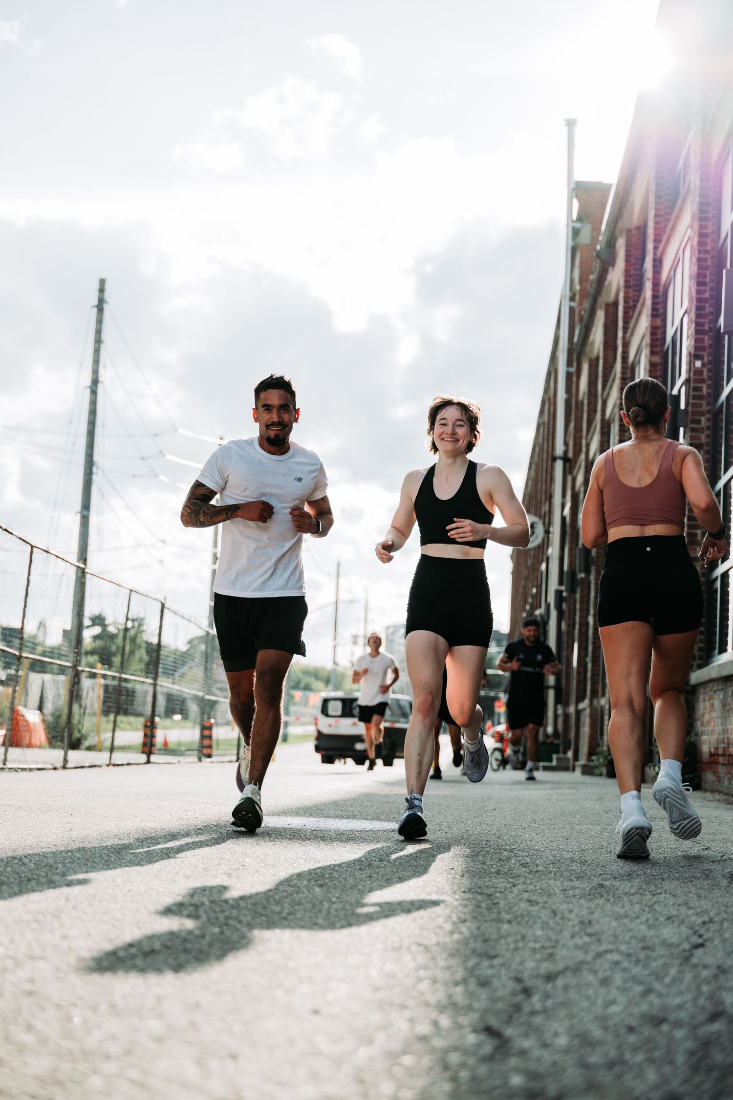 A sequence of five photos showing people running on a beach boardwalk from a low ground-level perspective.