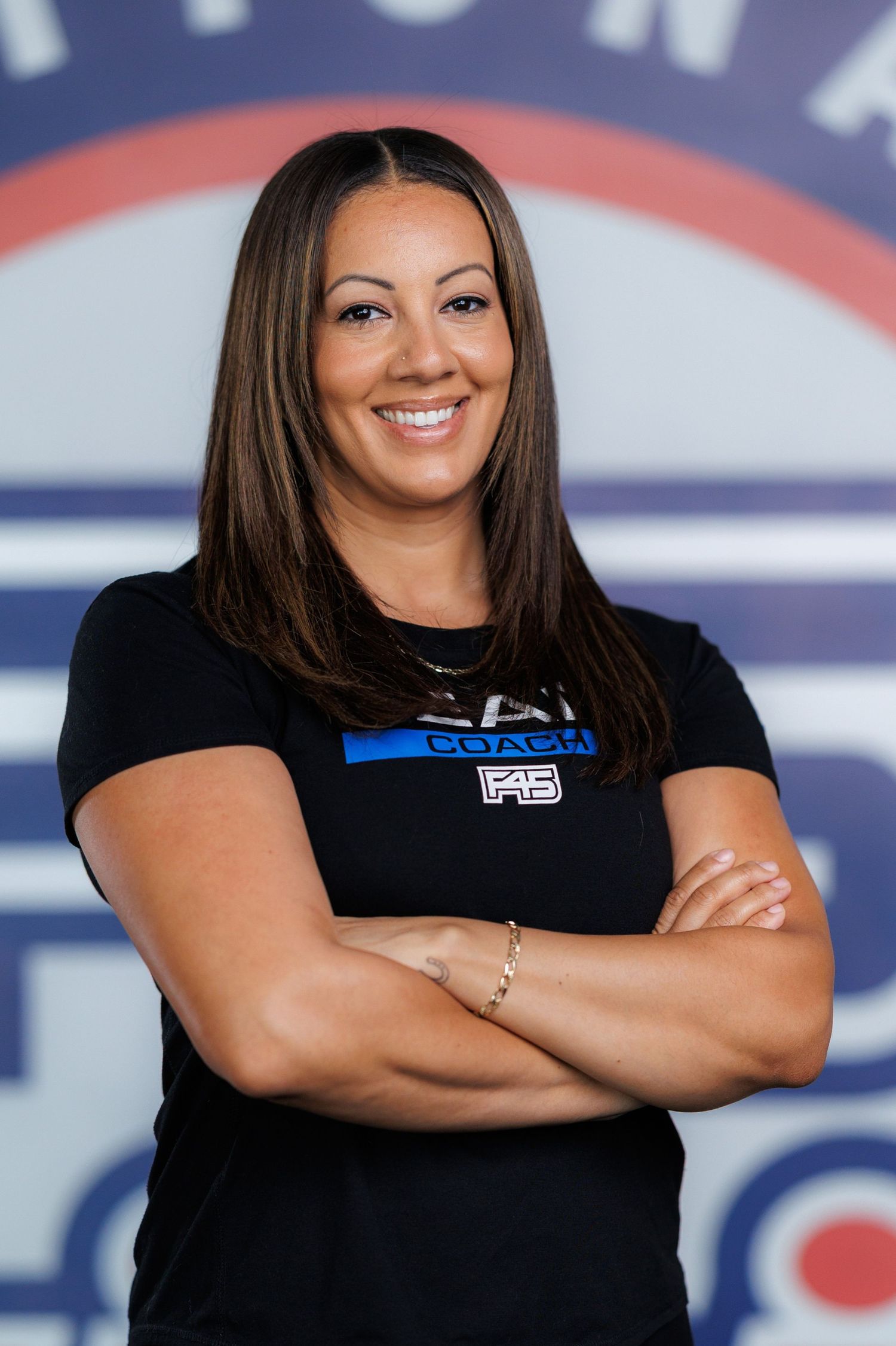 A person wearing a black t-shirt poses with crossed arms against a red, white and blue background.