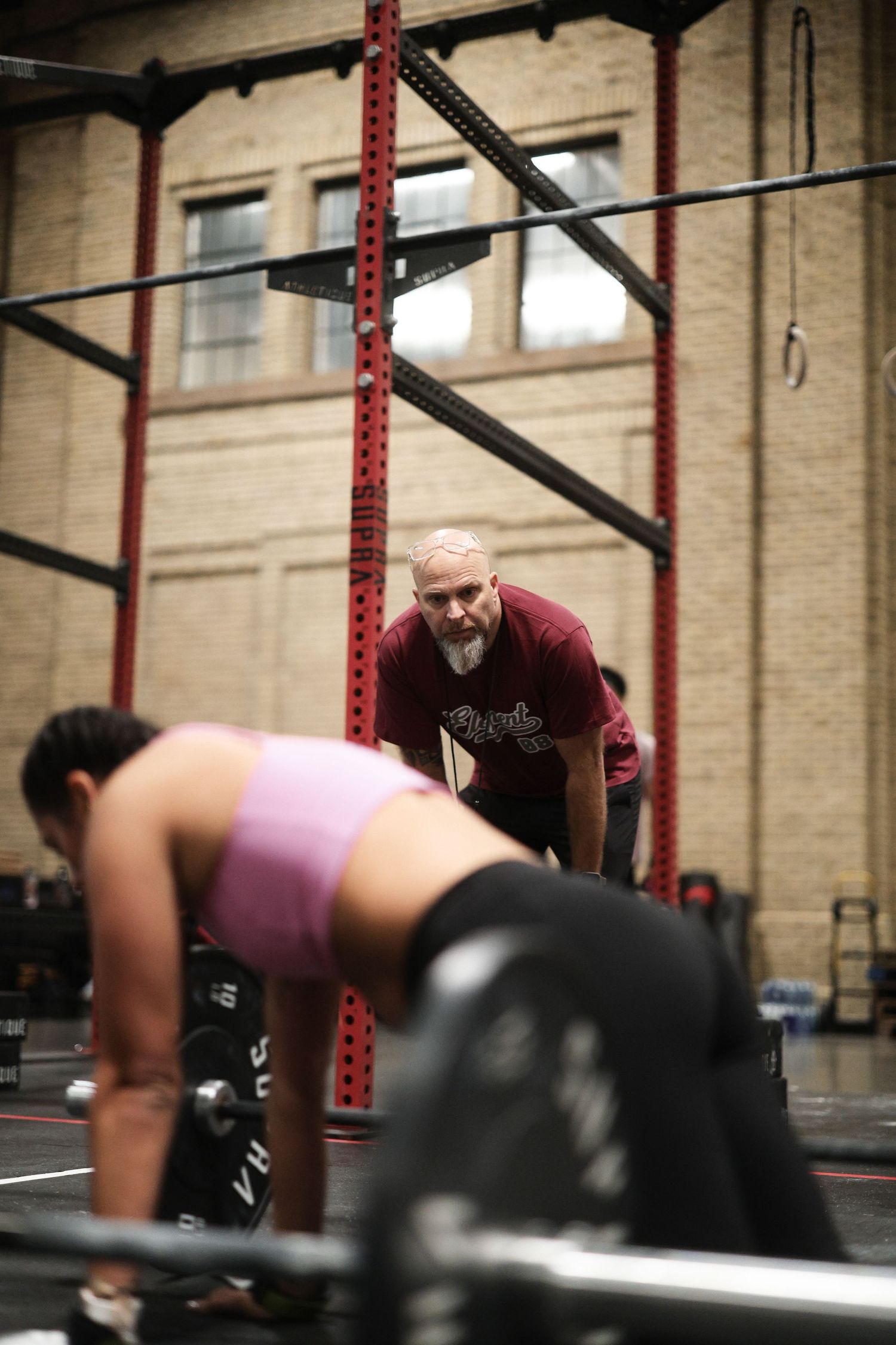 A sequence of photos showing someone performing a deadlift exercise in a CrossFit gym with red support beams.