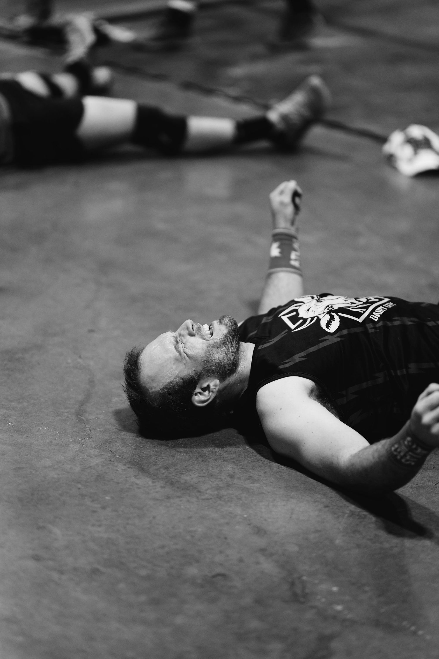 Exhausted athlete lying on the floor after an intense CrossFit workout in black and white.