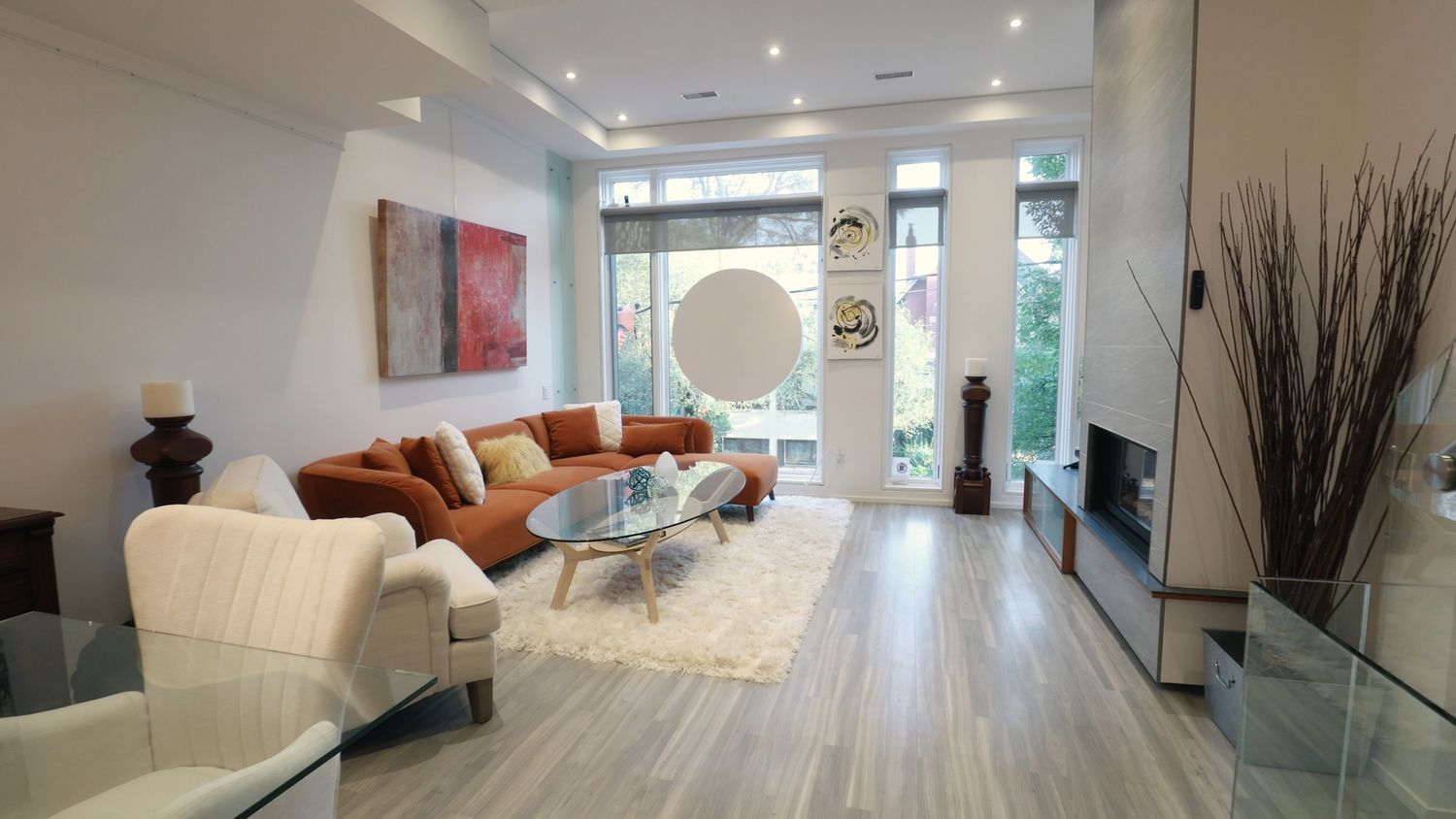 A sleek modern condo interior features a bright open layout with white walls, recessed lighting and contemporary furnishings.