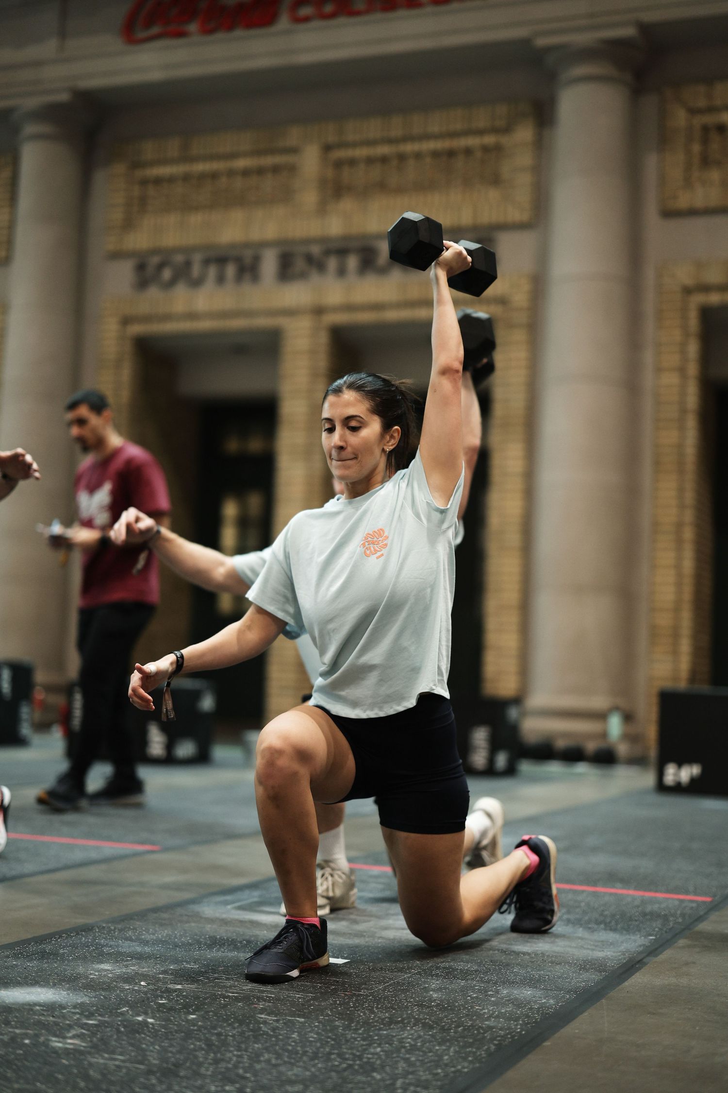 Athletes perform dynamic stretching exercises on a gym floor during a workout session.