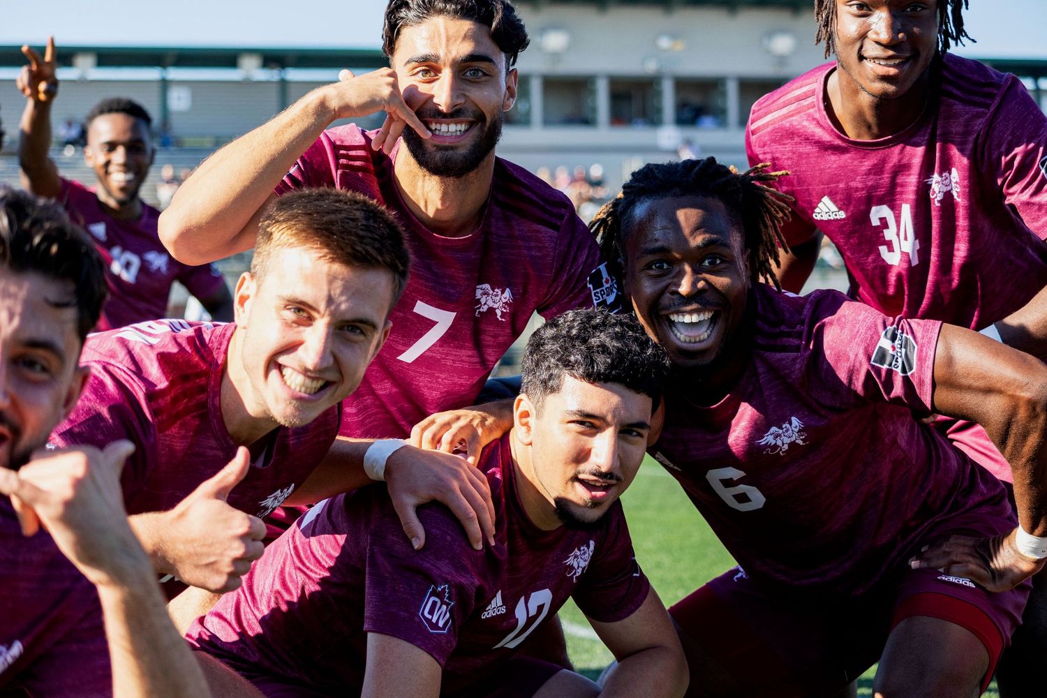 Soccer players celebrate together in pink jerseys with joyful expressions during a match.