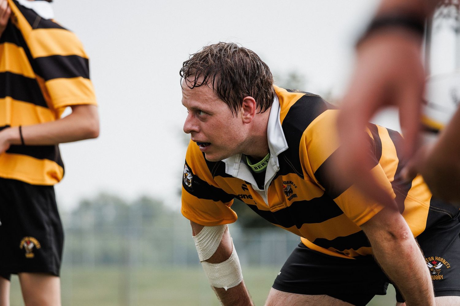 Athletes in yellow and black striped uniforms compete in a rugby match, showcasing intense physical action.