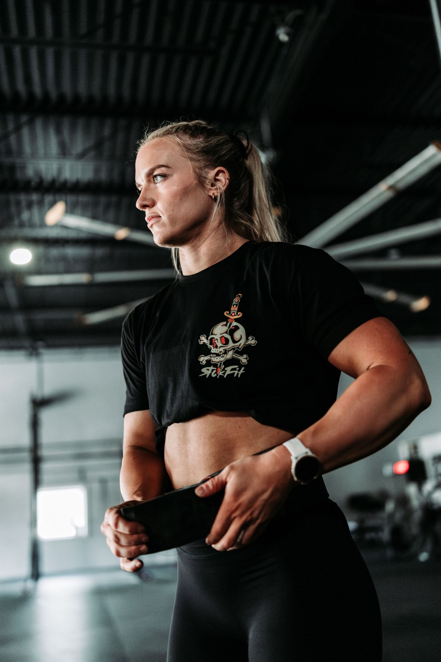 Athletic person in black workout gear demonstrating proper form in a gym setting.