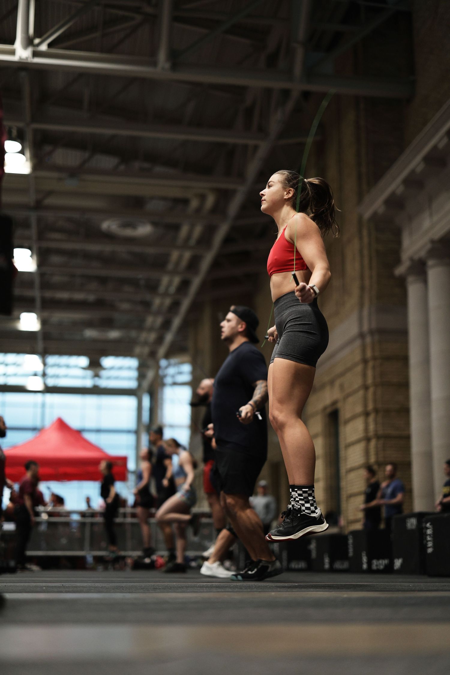 Athletes perform synchronized burpee exercises during an intense group workout session in an industrial gym space.