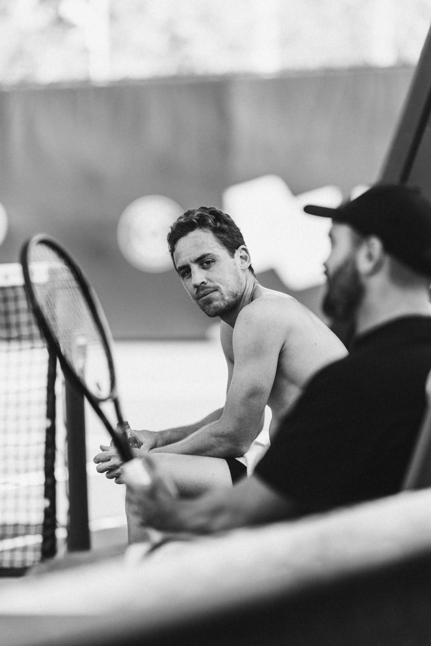 A black and white sequence of tennis player preparing to serve, shown in multiple overlapping frames.