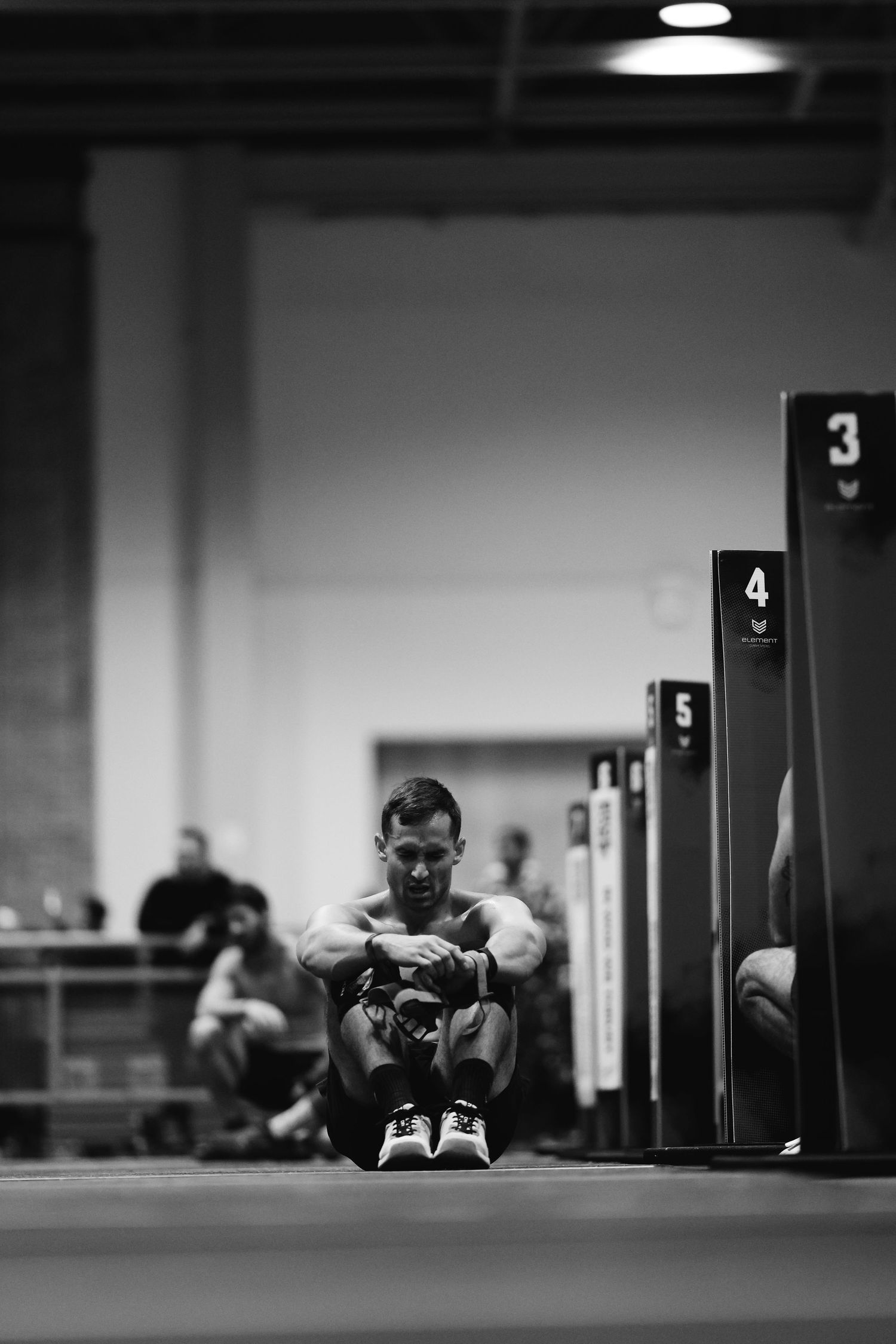 Black and white image series showing a person doing pushup exercises in a gym with numbered doors visible in background.
