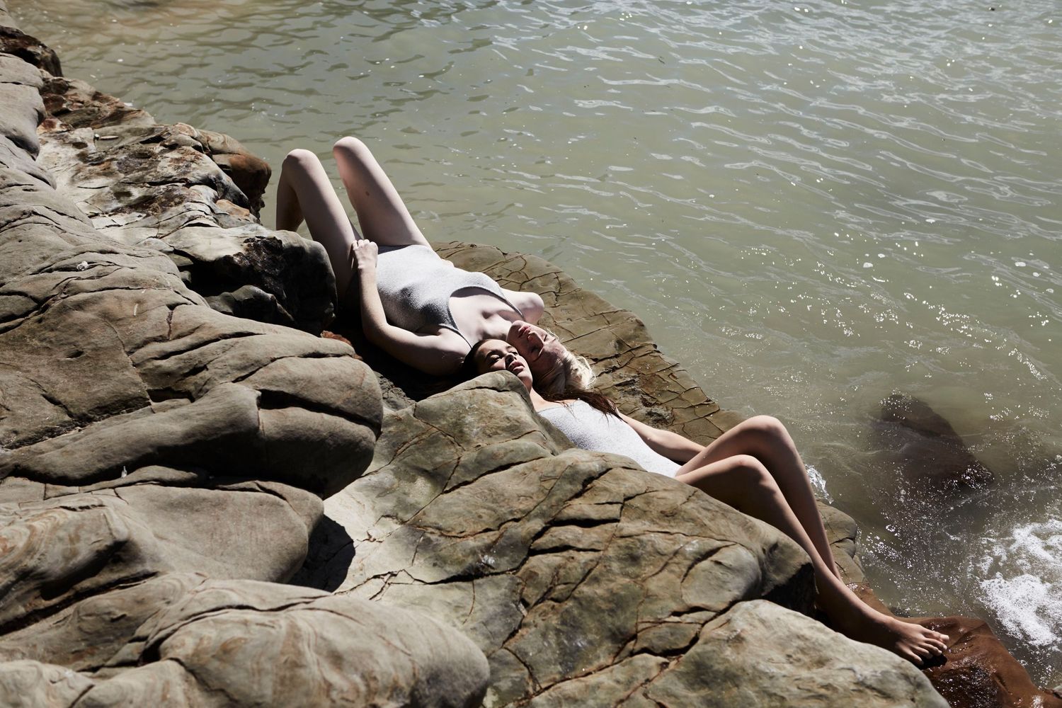 Two women sunbathing on rocks