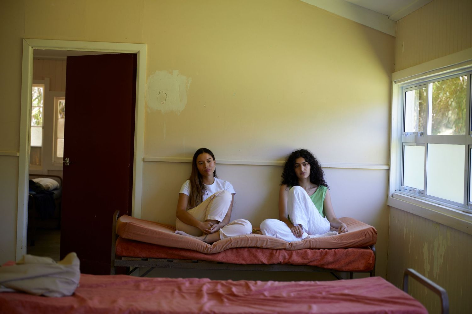 Two women sitting on mattresses