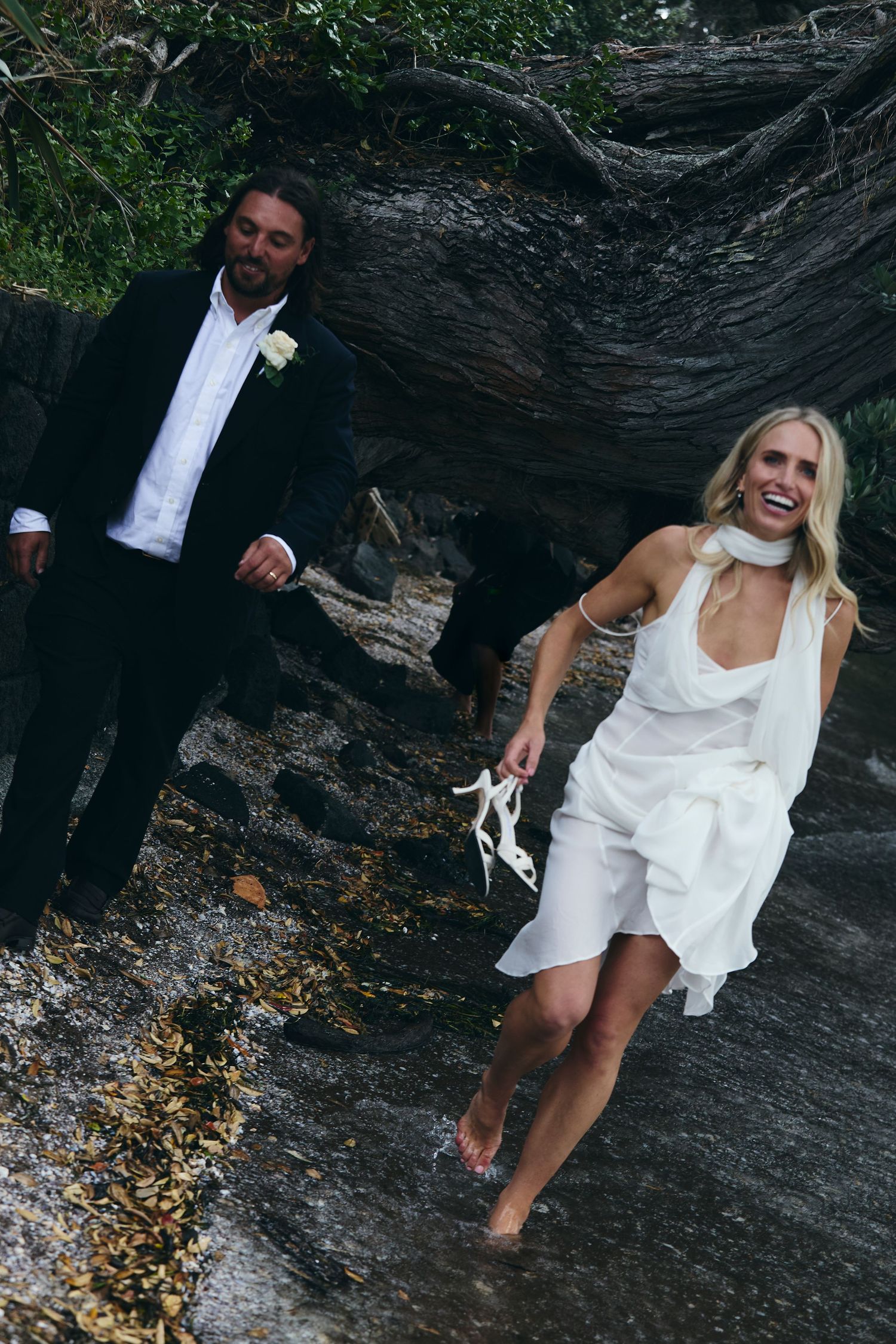 Bride and groom running along beach