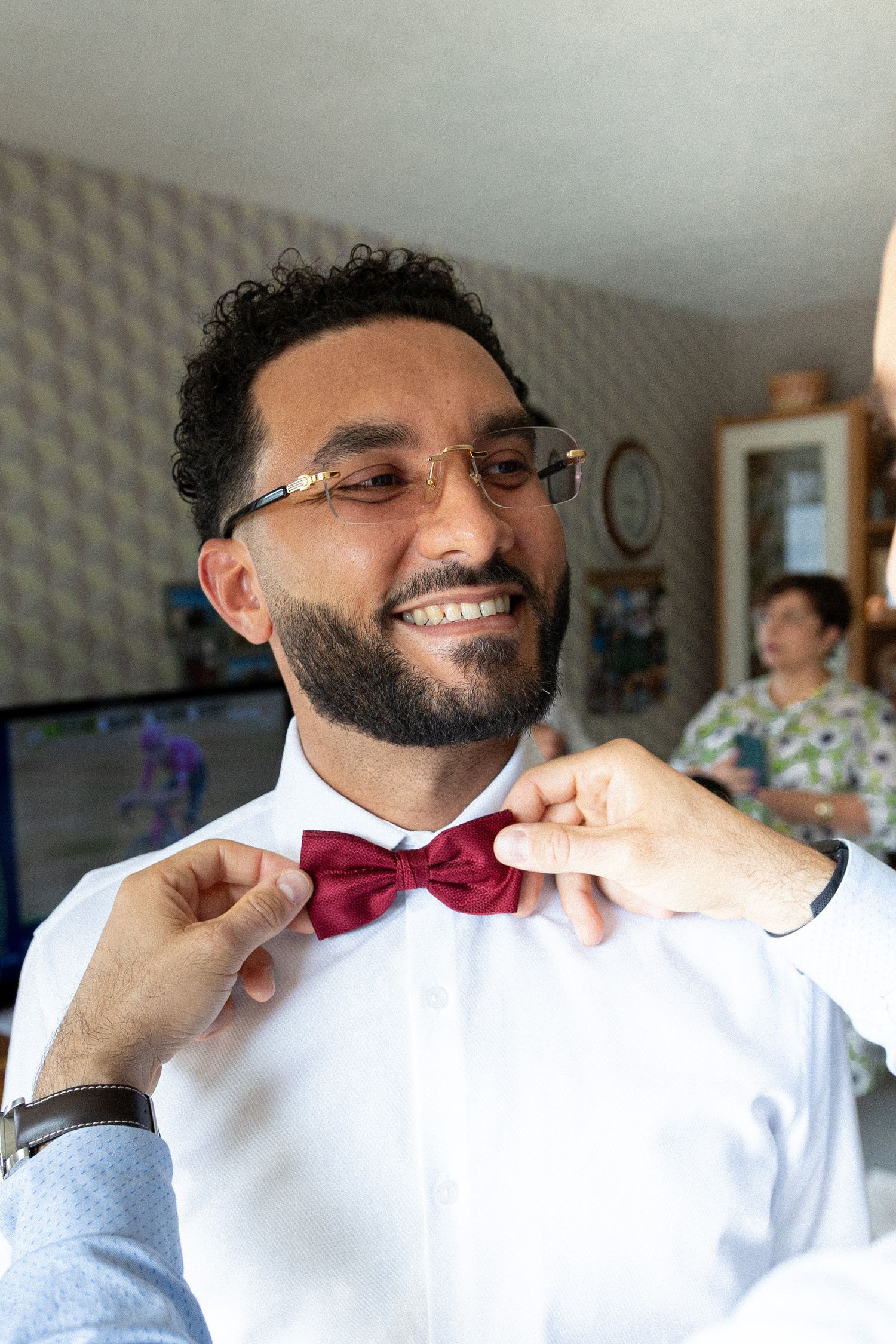 Sequence showing the adjustment of a burgundy bow tie against a crisp white shirt.