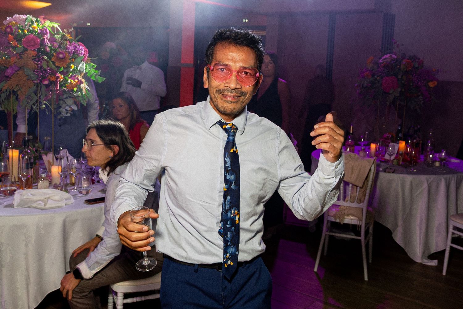 Wedding reception guest enjoying drinks and dancing in a festively lit venue.