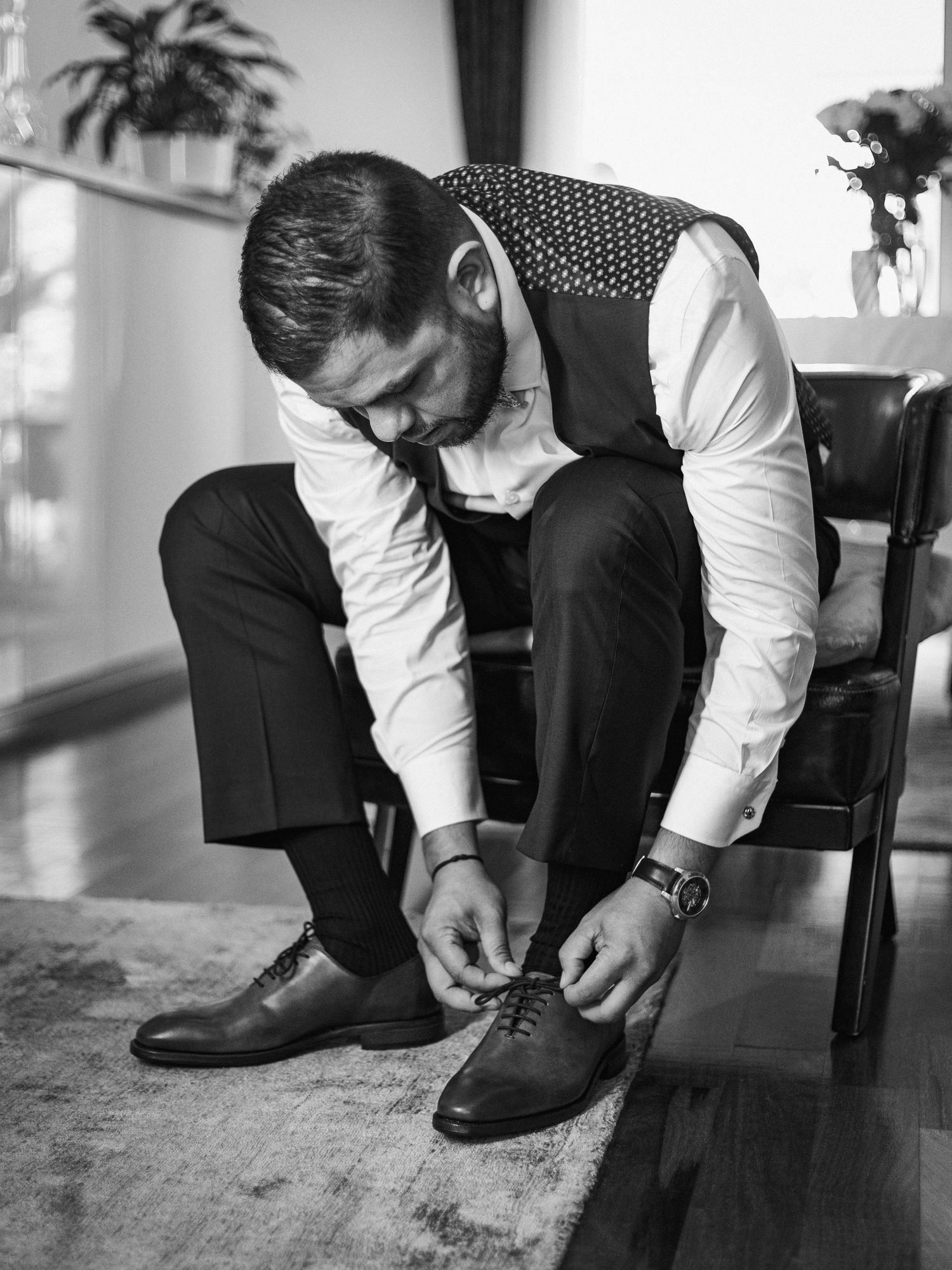 A formal black and white attire with focus on tying dress shoes.