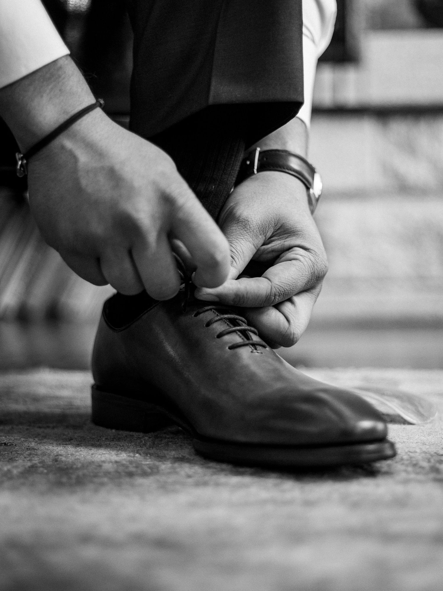Close-up of hands tying formal black leather dress shoes.