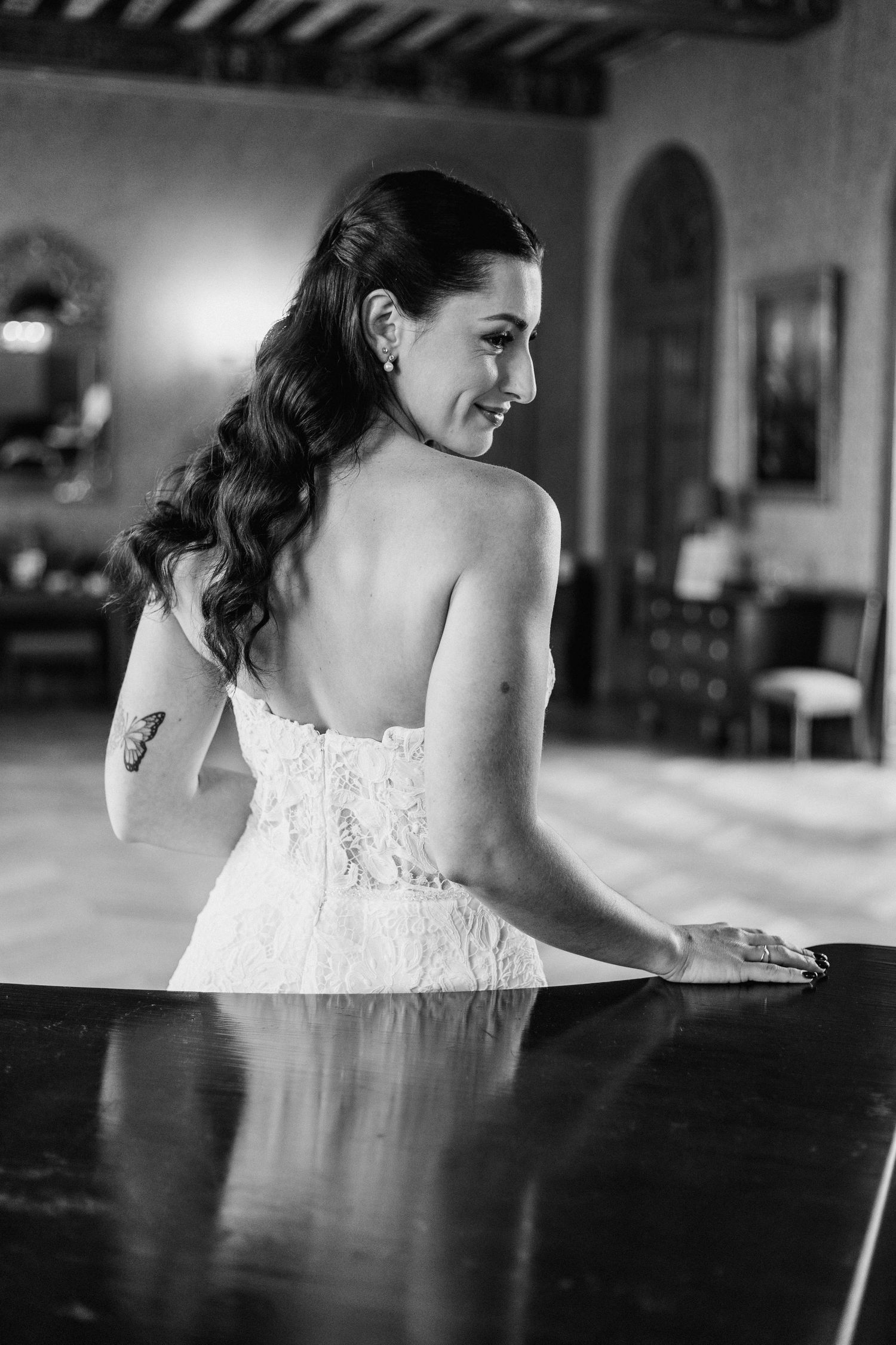Bride in lace dress captured in artistic black and white photos at piano.