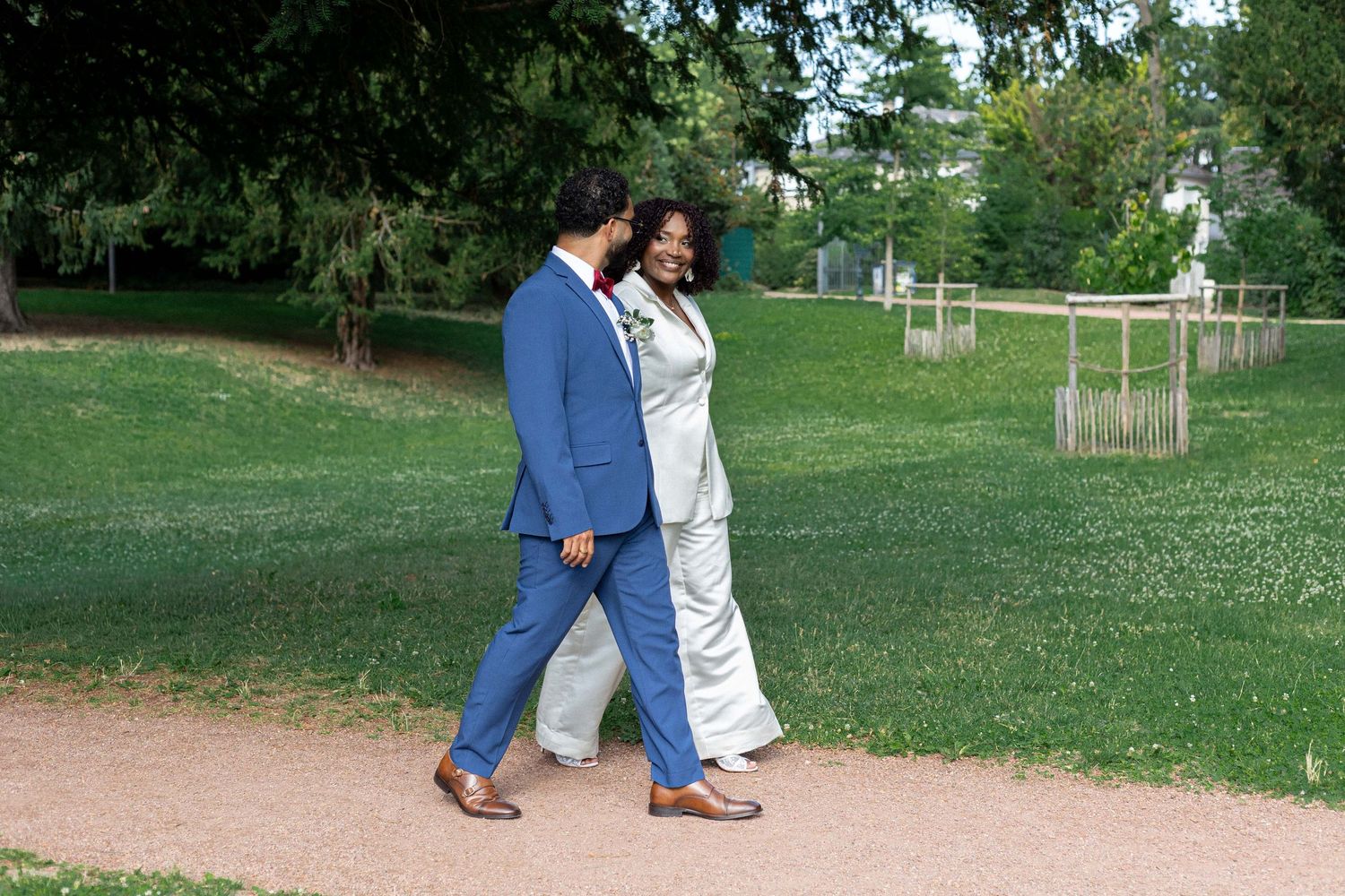 People walking on a grassy path in a park setting during a sunny day.
