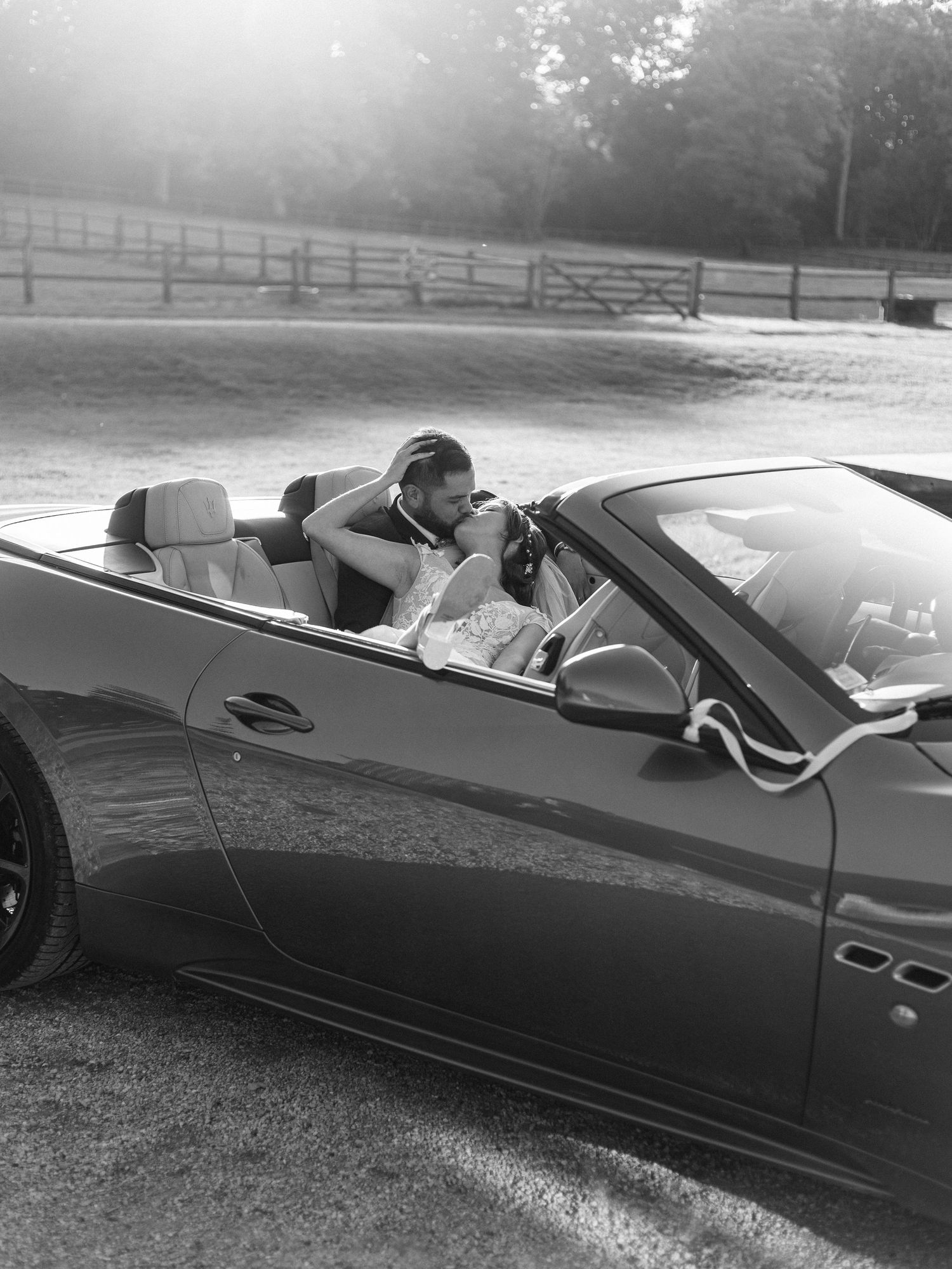 A luxury convertible car parked in a countryside setting at sunset.