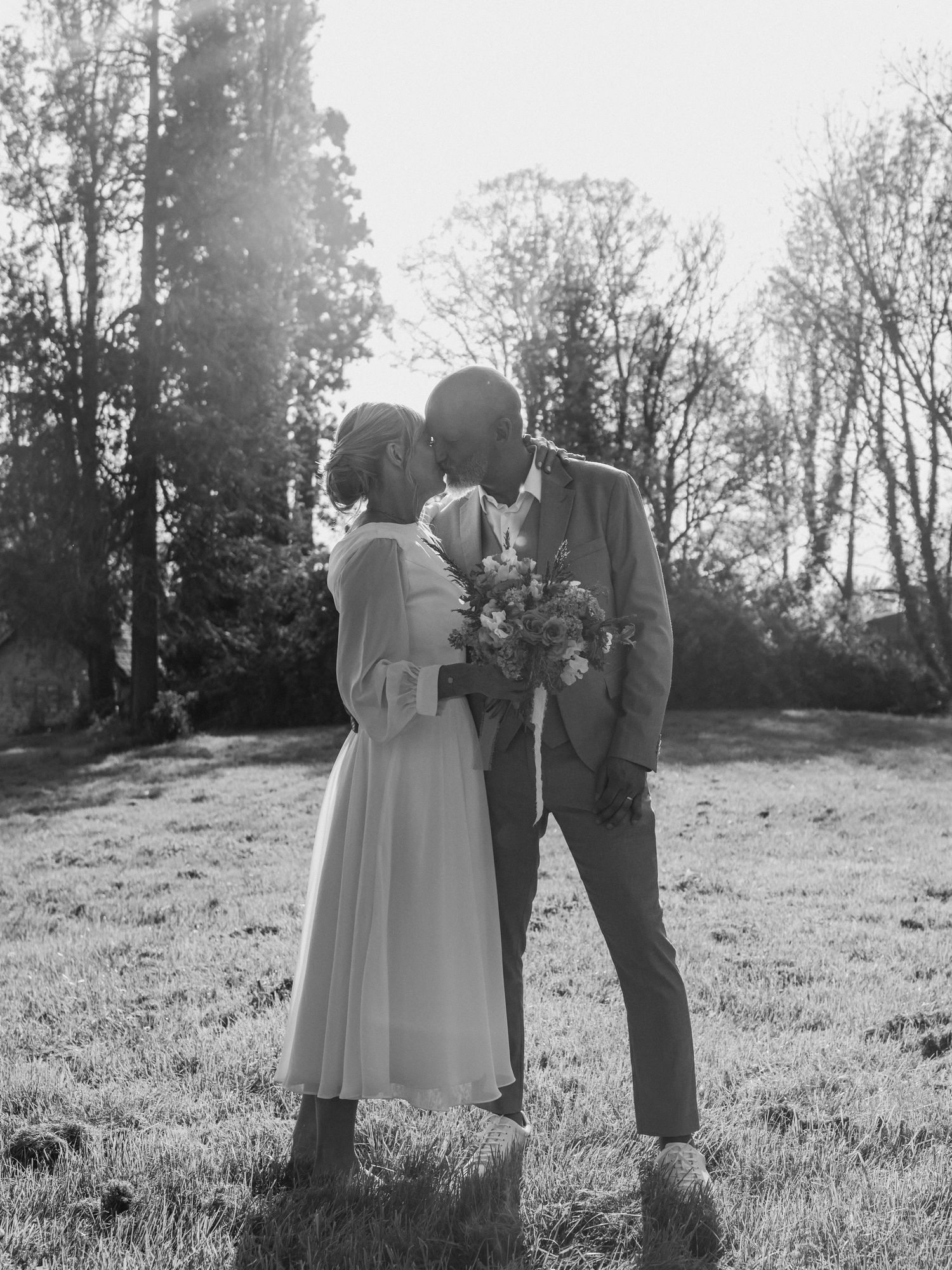 A romantic black and white photo series captures a couple's intimate moments in a sunlit meadow.