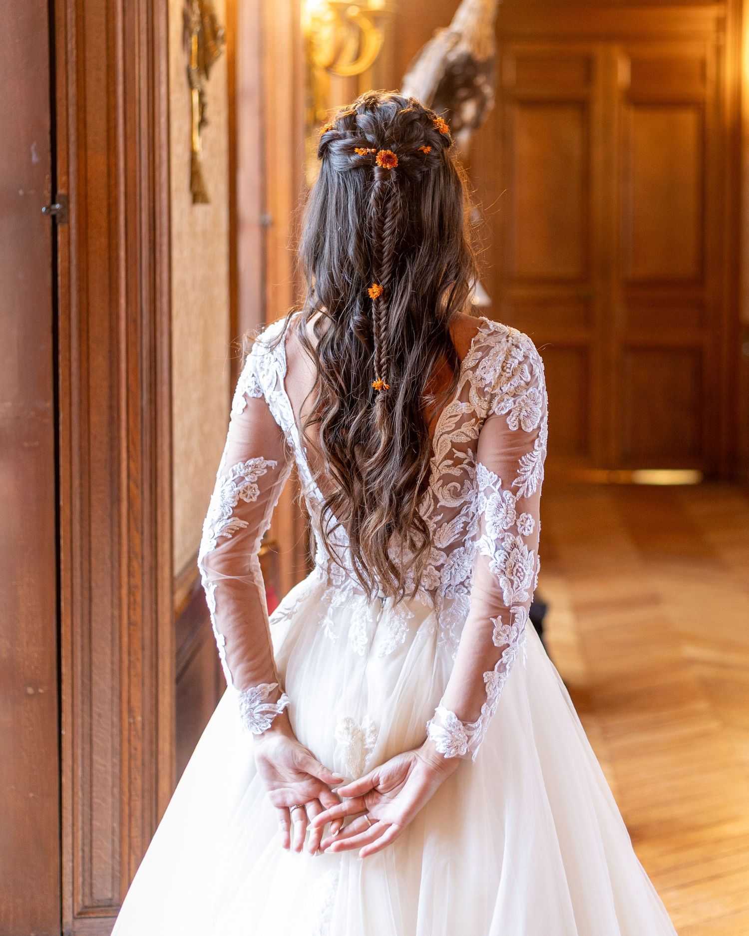 Wedding dress with long lace sleeves photographed in an elegant wood-paneled room.