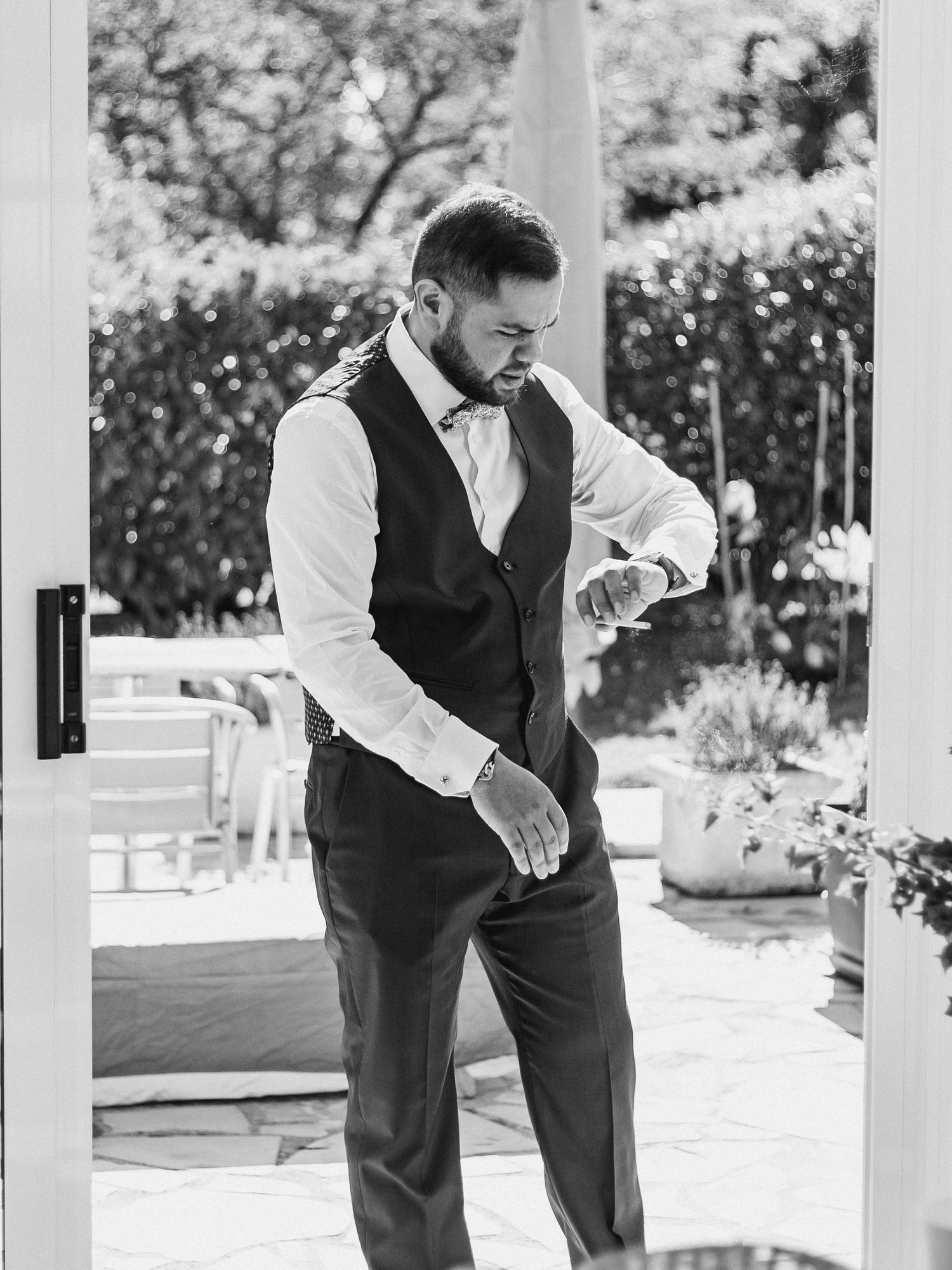 A formal outfit with vest and bowtie being adjusted outdoors.
