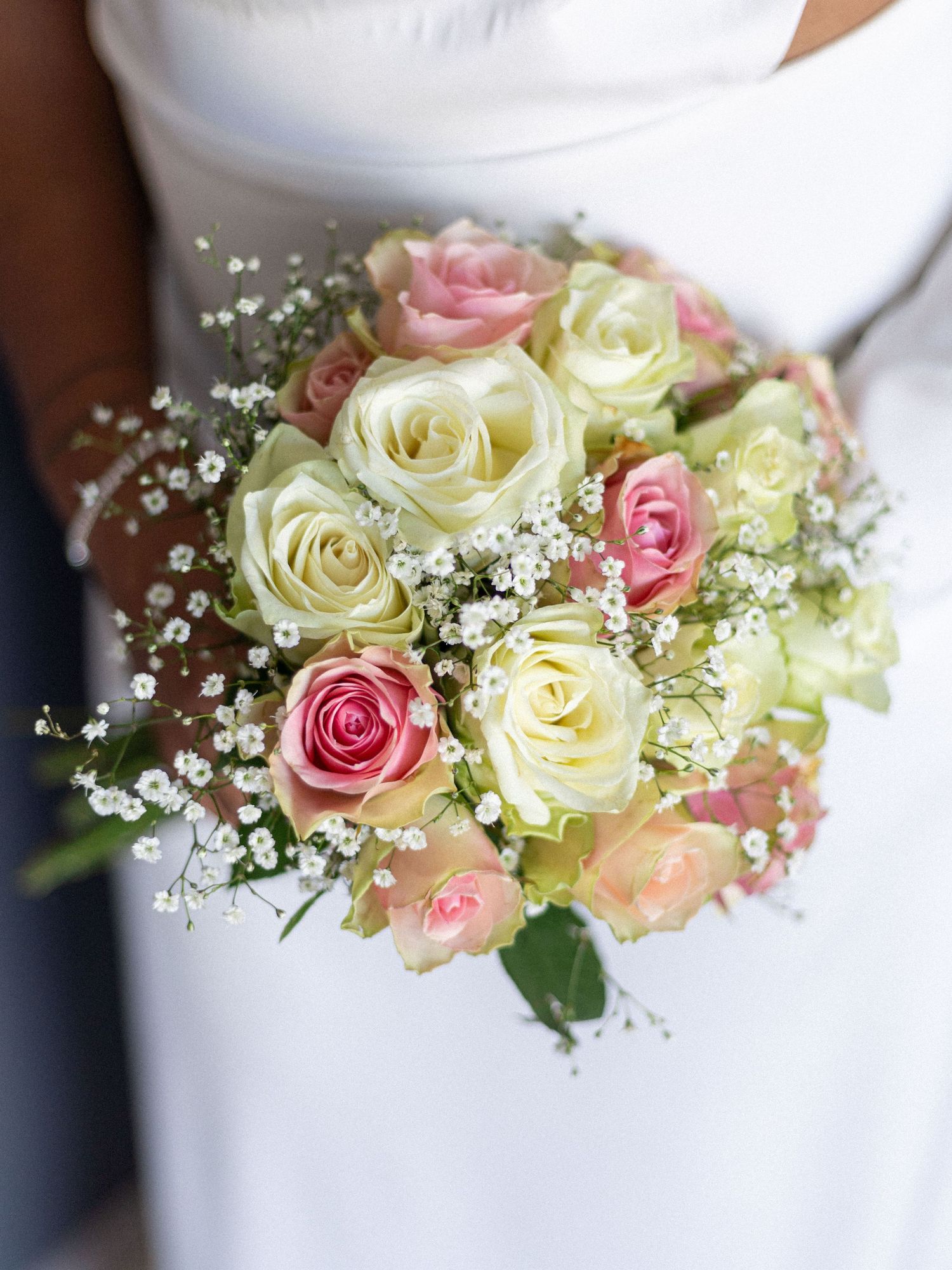 Elegant bridal bouquet featuring cream and pink roses with delicate baby's breath accents.