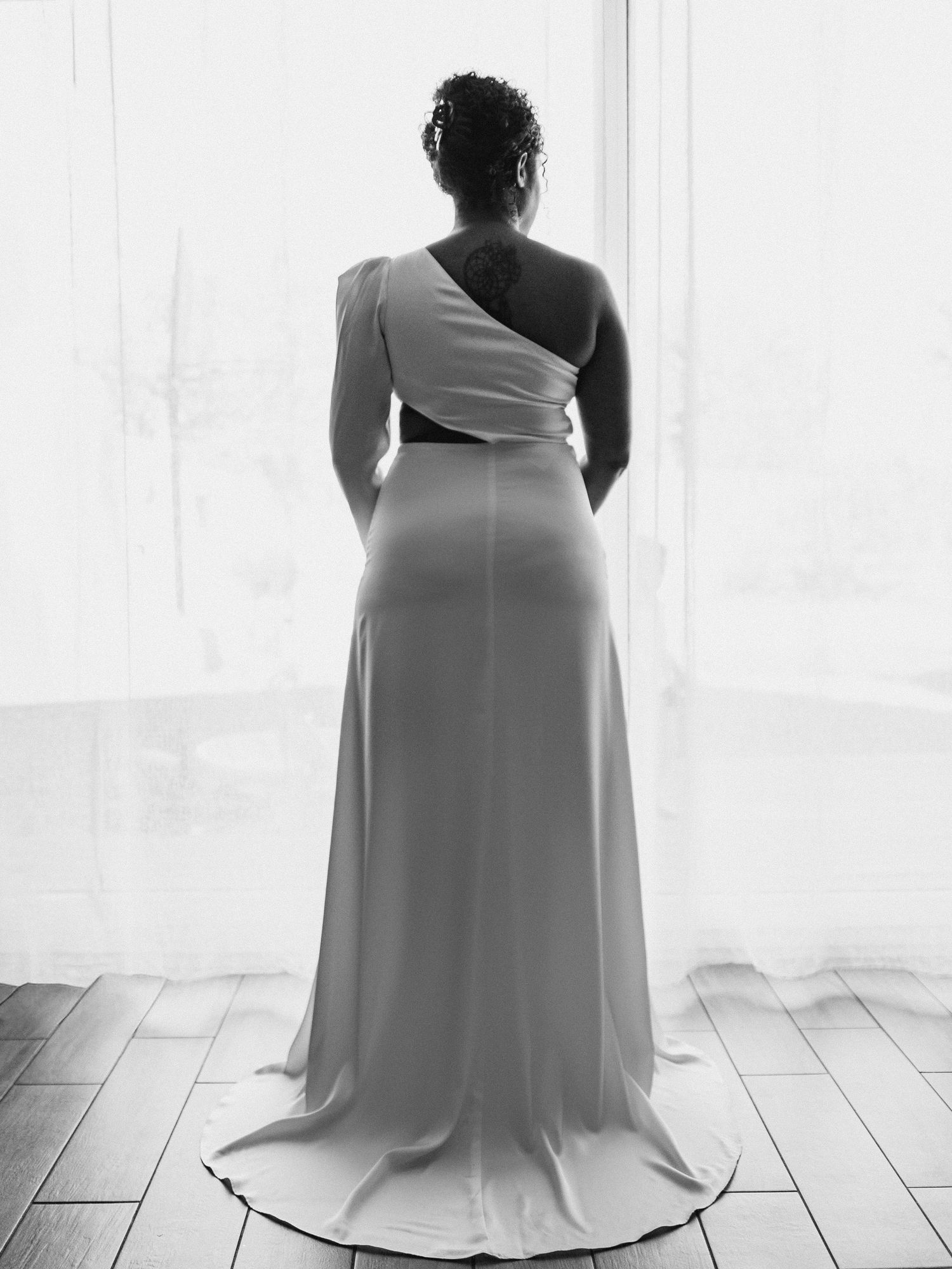 Minimalist black and white bridal portraits showcasing elegant dress silhouette against window light.