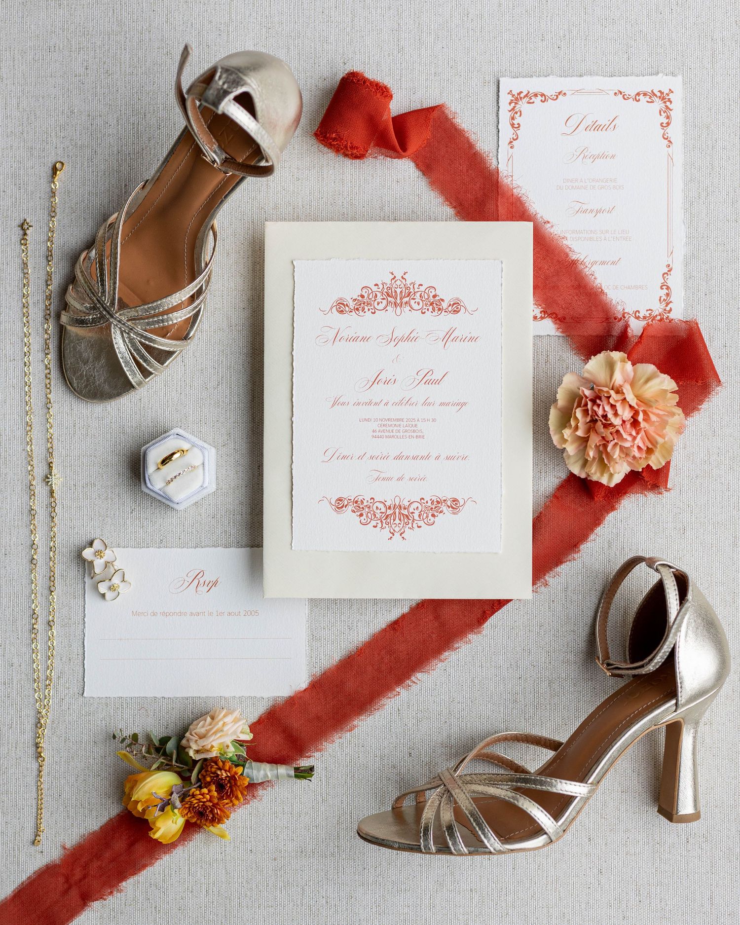 Wedding invitation suite with coral red silk ribbon, peach flowers, silver heels and delicate stationery details.