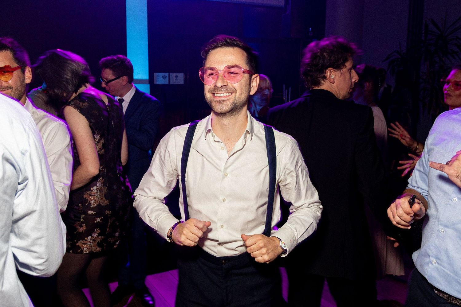 Guest dancing and celebrating at a wedding reception with purple mood lighting.