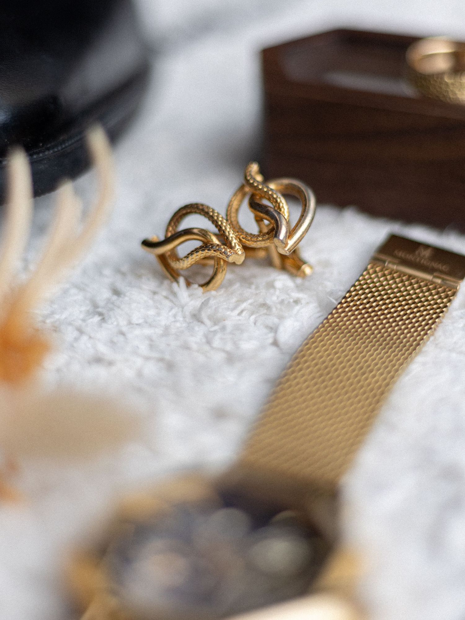 Gold mesh jewelry and accessories arranged on white lace fabric.