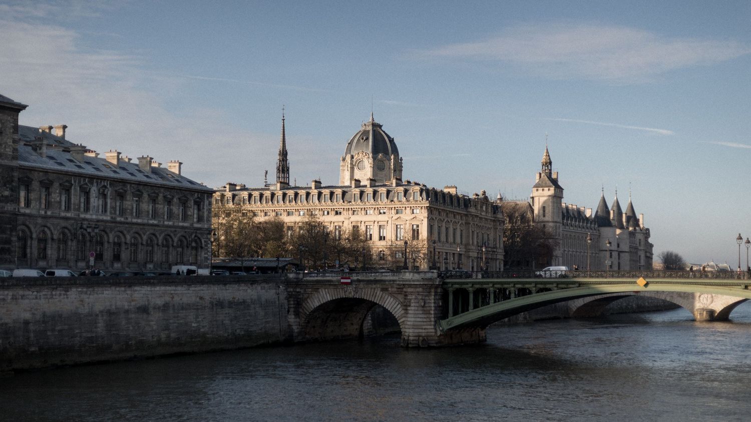 Panoramic view of historic buildings and bridges along the Seine River in Paris during golden hour.