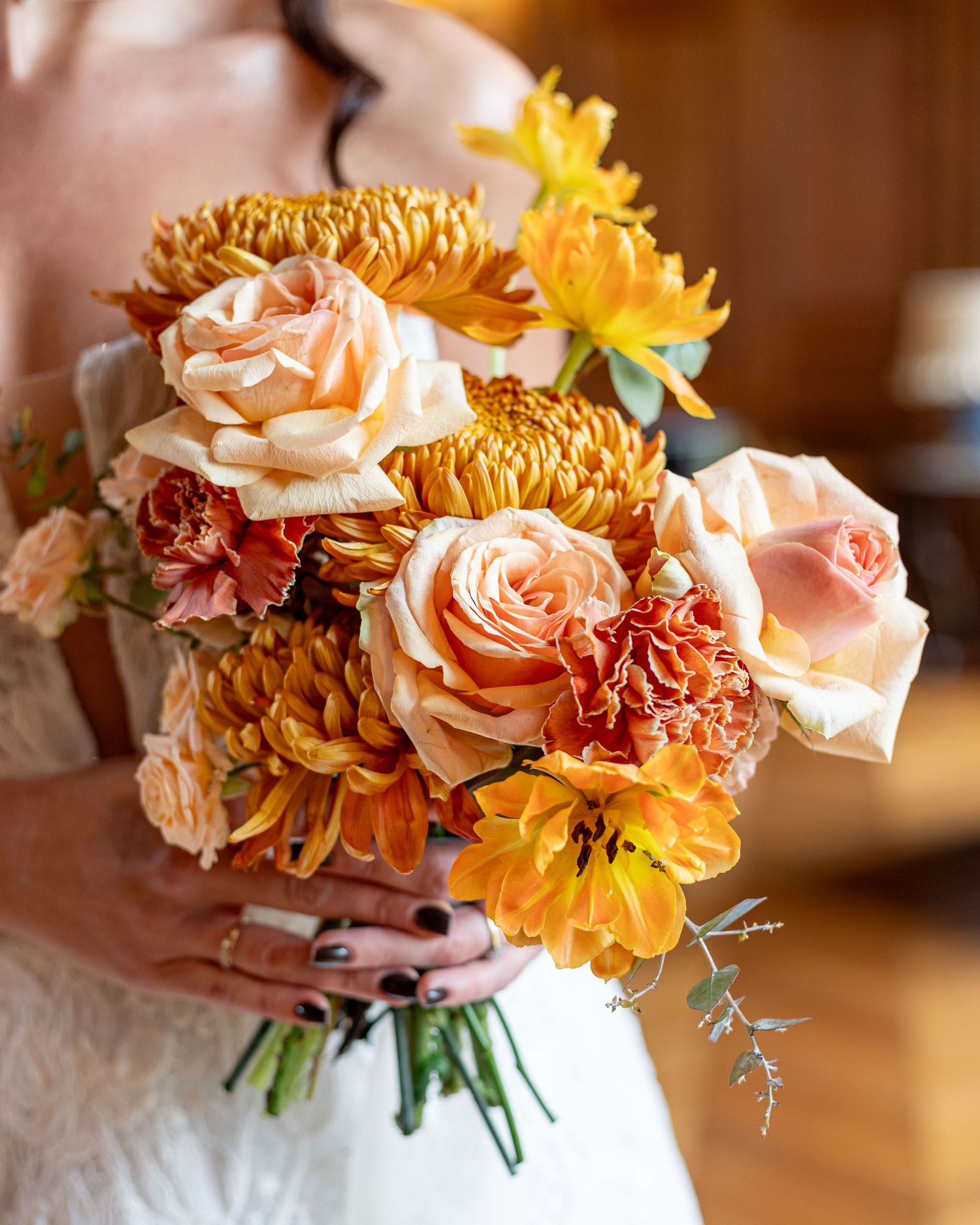 A romantic floral arrangement featuring peach roses, orange dahlias and yellow chrysanthemums in warm autumn tones.
