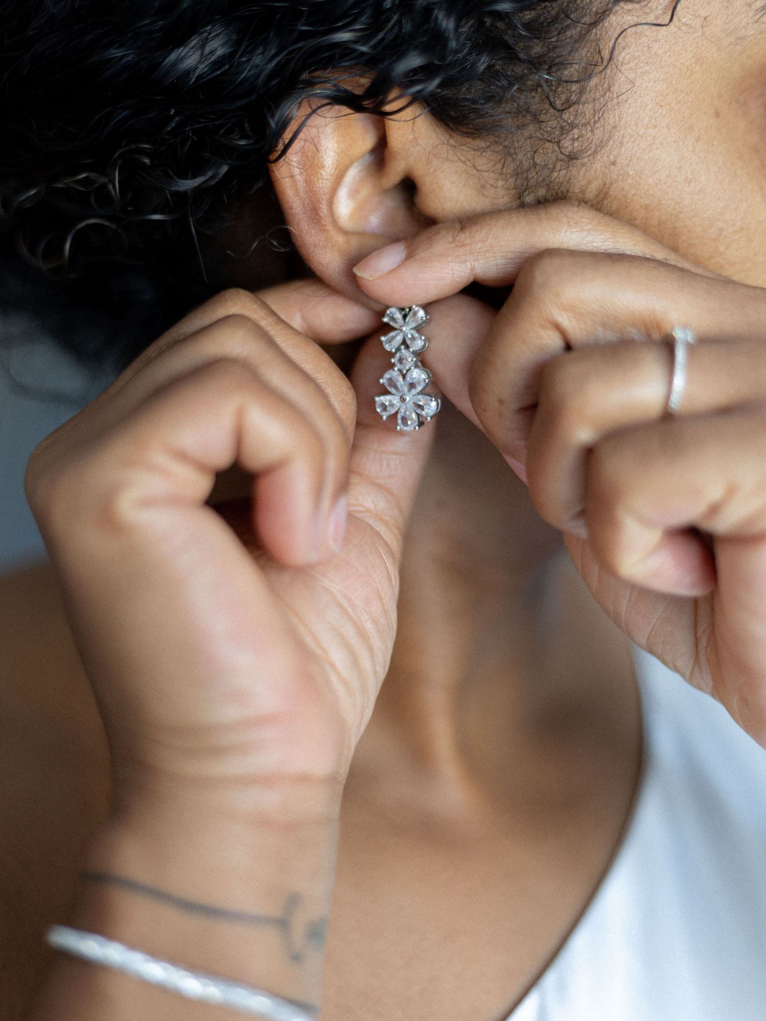 Close-up details of sparkling diamond earrings and jewelry against a light background.