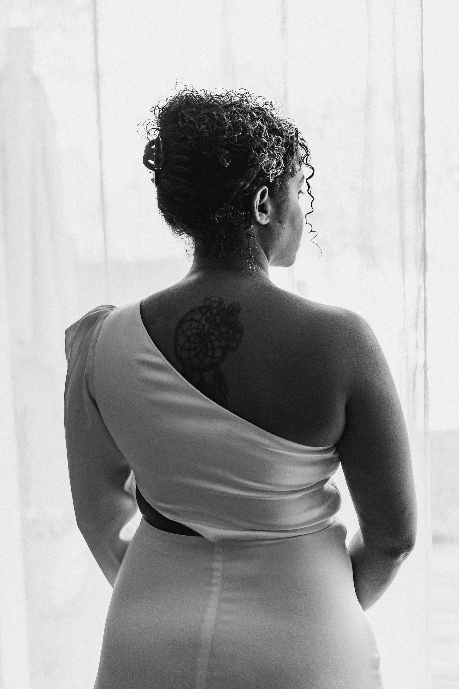 Artistic black and white portrait series showing a flowing white dress against a bright window.