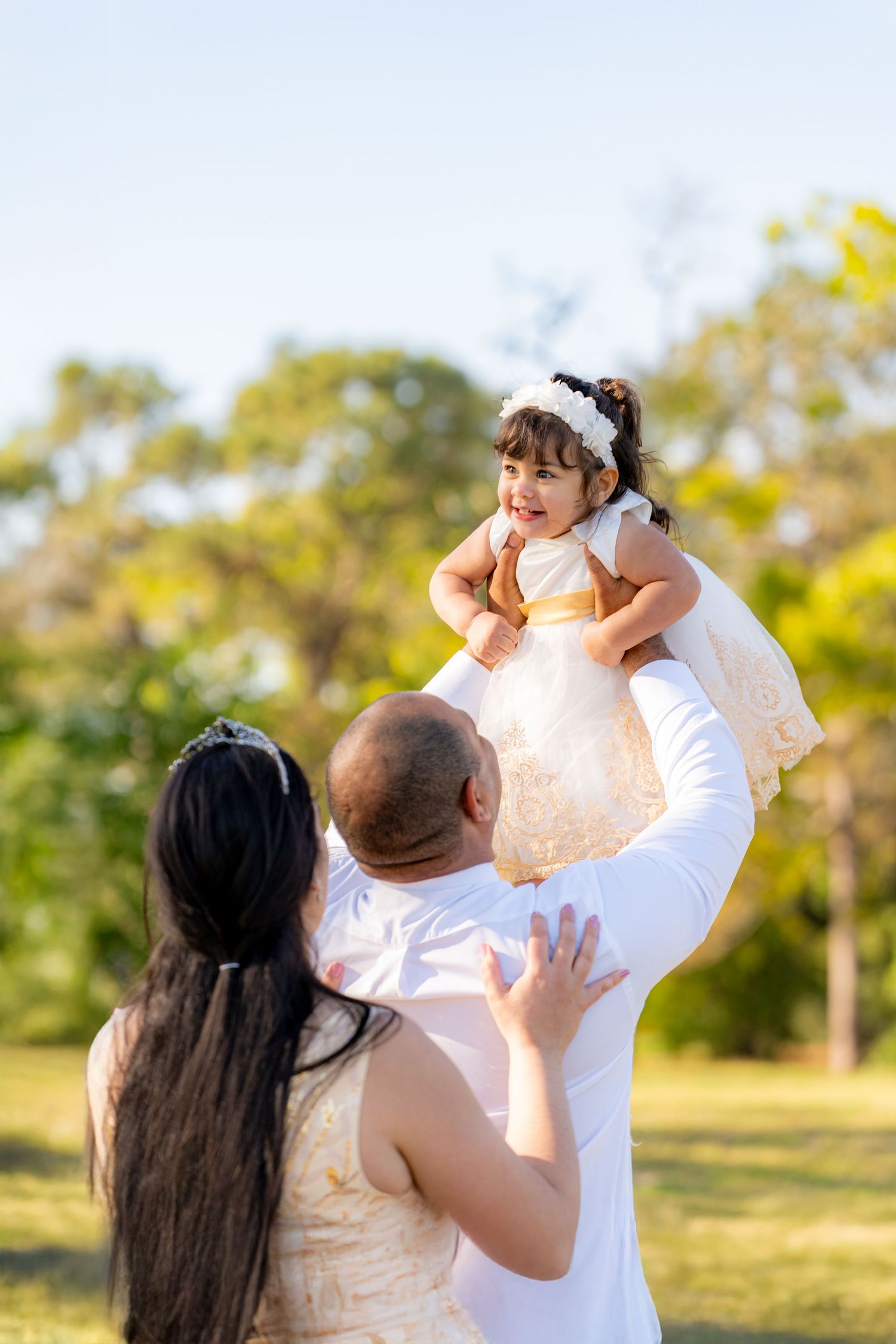 A joyful family moment captured during a sunny afternoon in a park setting.