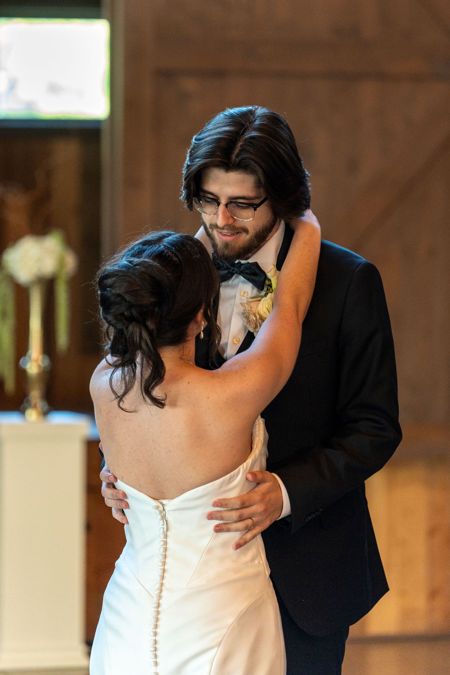 Bride and groom share intimate first dance embrace in rustic barn wedding venue.