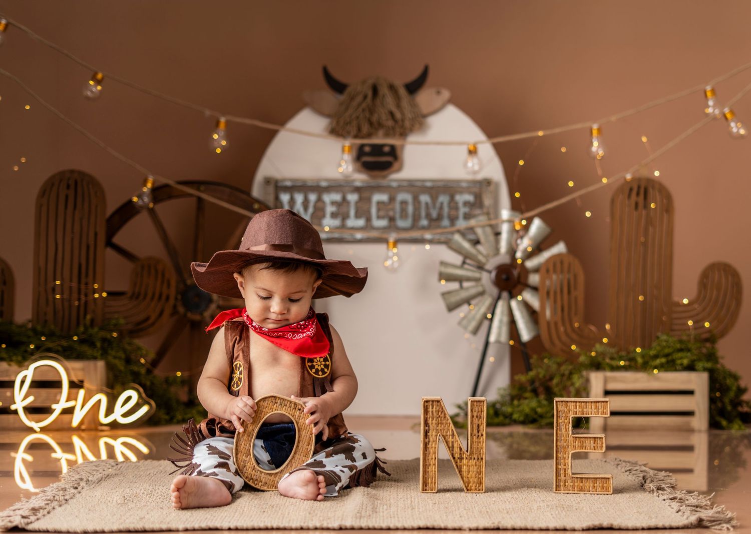 Rustic cake smash photo setup with string lights, wooden decor, and vintage elements for first birthday celebration.