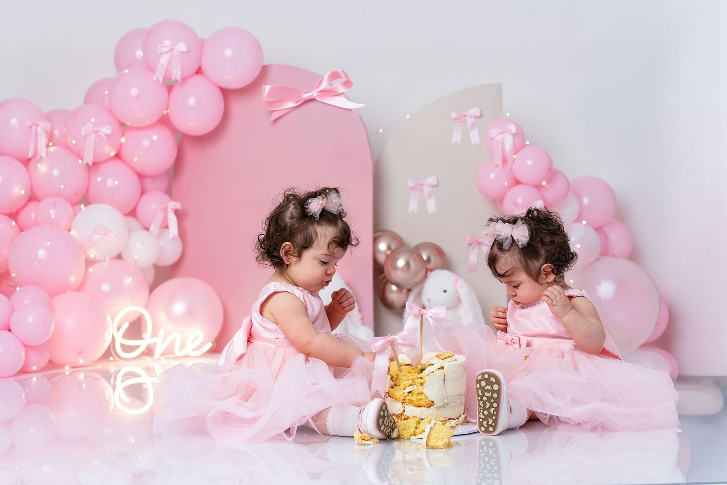 Pink balloon decorations and neon lights create a romantic ambiance for a party setting.