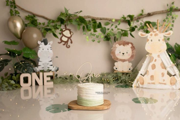 Safari themed first birthday display with wooden ONE letters, plush animals, and greenery garland.