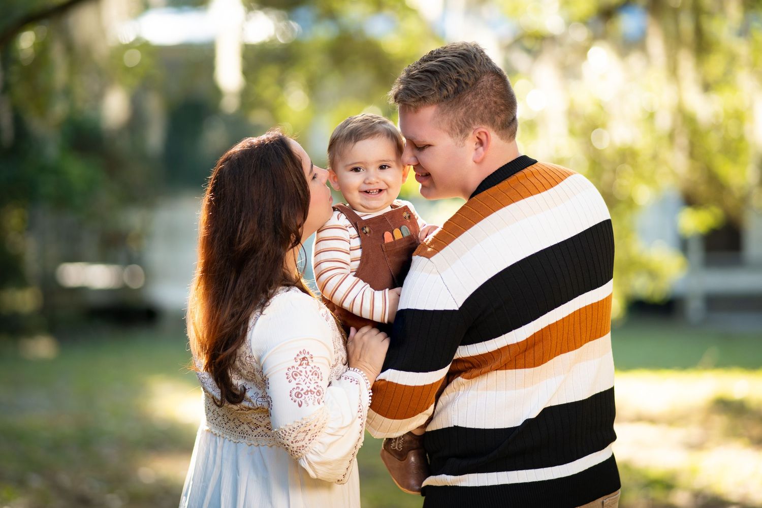 A loving family shares tender moments together in a sunlit outdoor setting during a photo session.