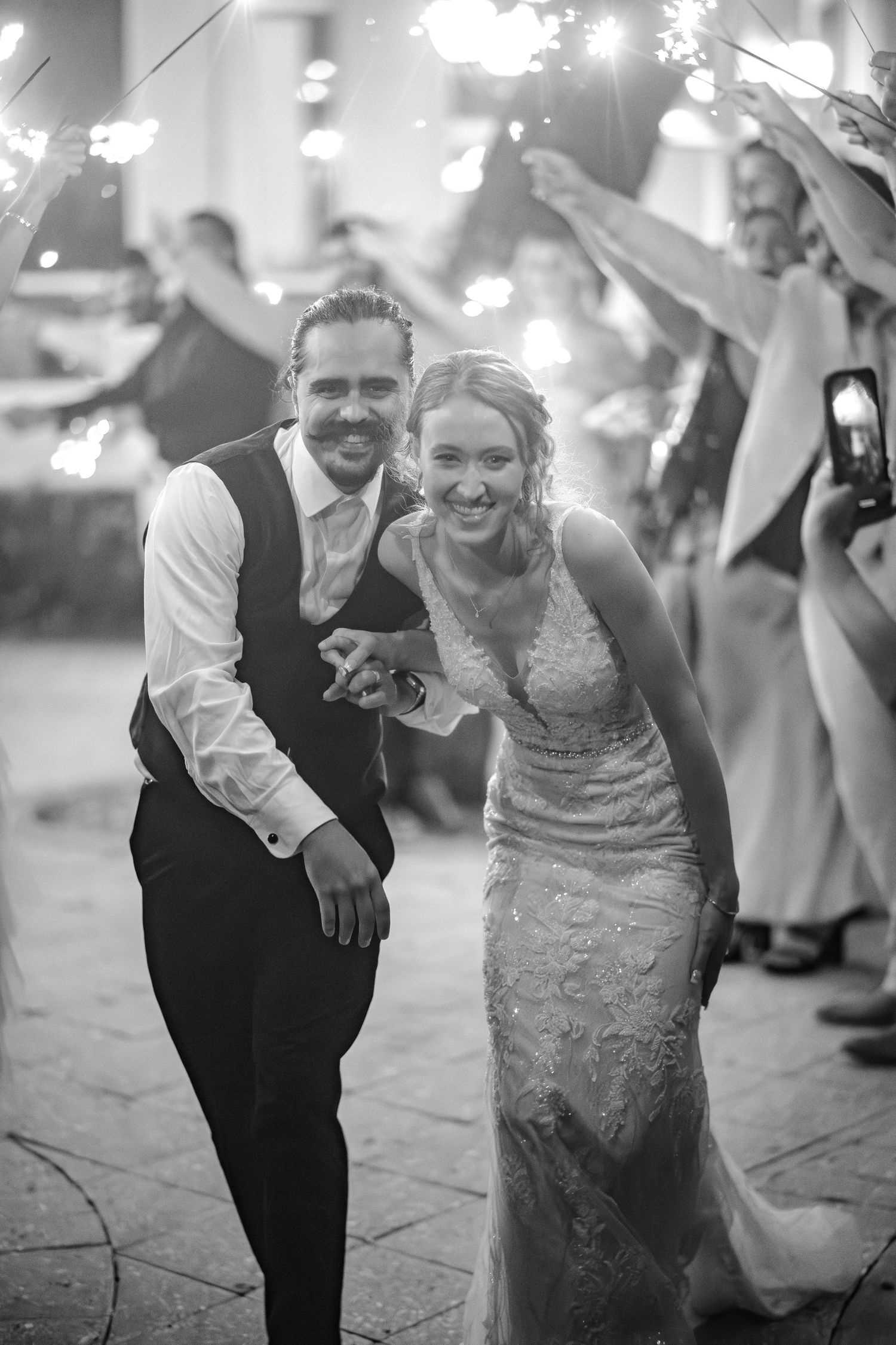 A bride and groom share a joyful moment during their sparkler exit at an evening wedding reception.