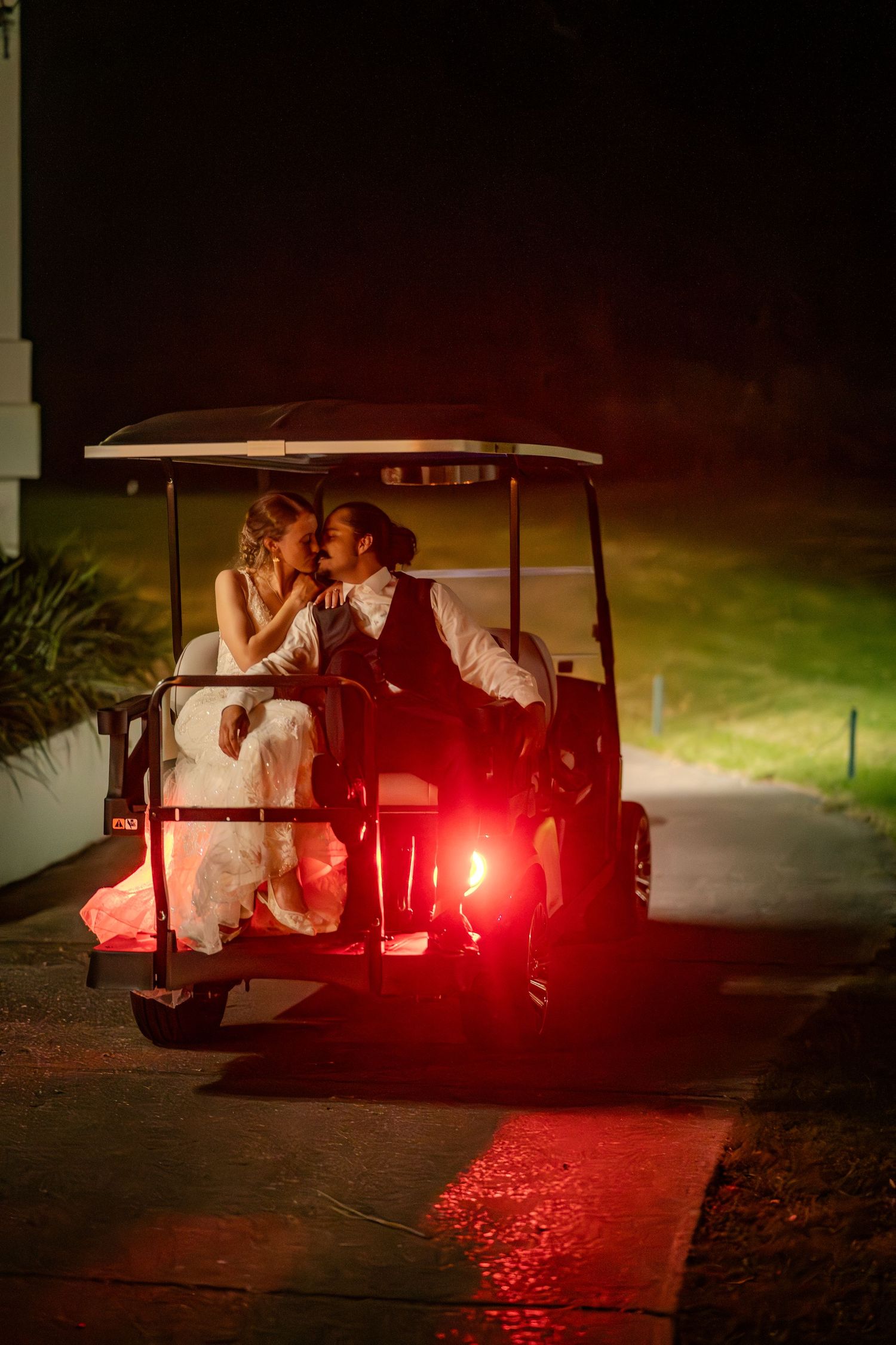 Wedding couple sharing intimate moments in golf carts at night with dramatic red lighting effects.