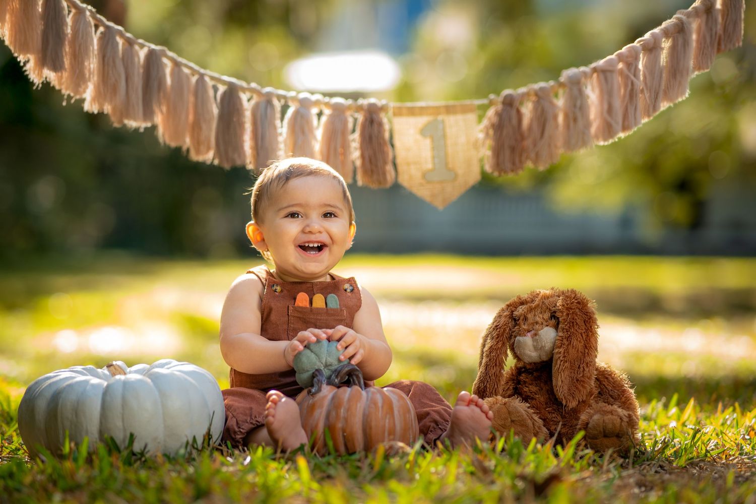 A festive outdoor autumn scene with pumpkins and decorative bunting strung overhead in warm sunlight.