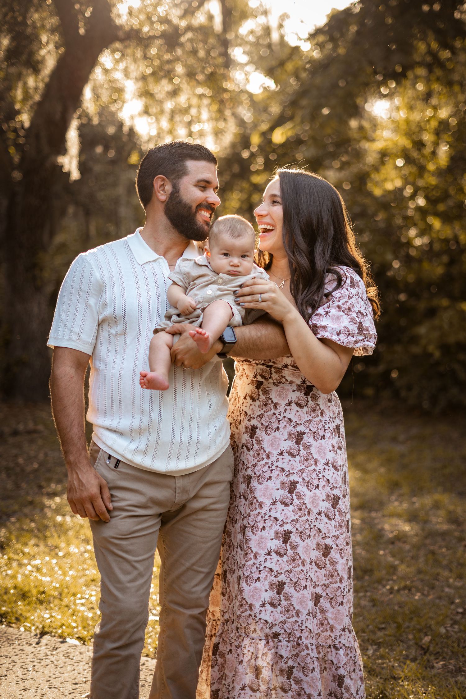 A family shares loving moments together in a sun-dappled forest setting during golden hour.